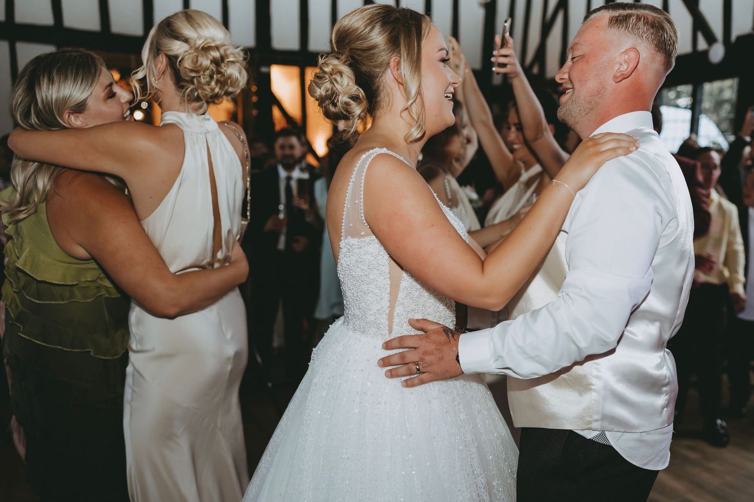 Intimate dance moment captured at wedding reception with guests in background.