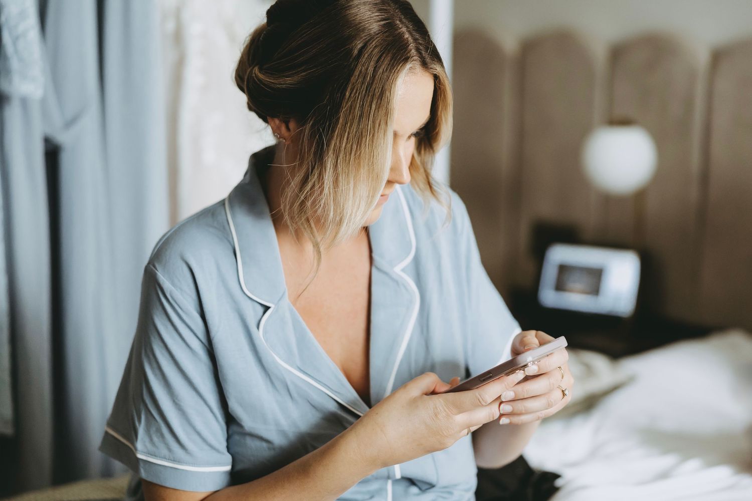 Person in light blue clothing relaxing in a comfortable bedroom setting.