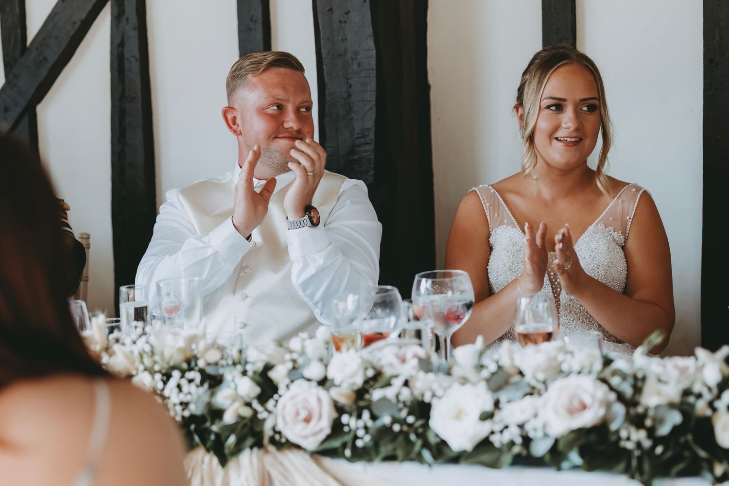 Wedding party members sharing laughs and reactions during reception toasts.