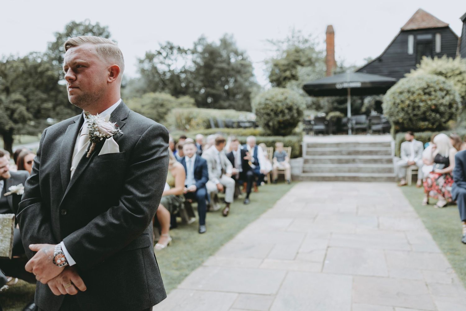Garden wedding ceremony with guests gathered along stone walkway.
