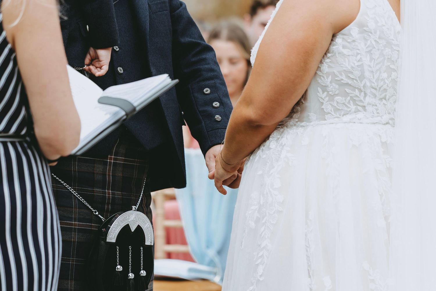 Close-up of wedding ceremony details showing traditional Scottish kilt and white dress.