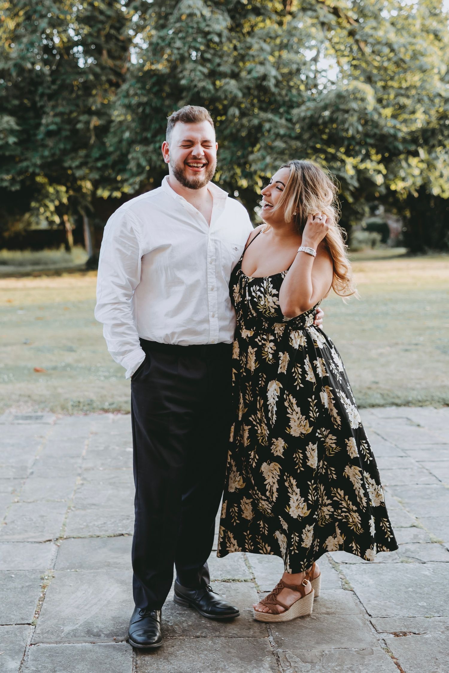 Couple in formal wear sharing a joyful moment on stone patio during event.