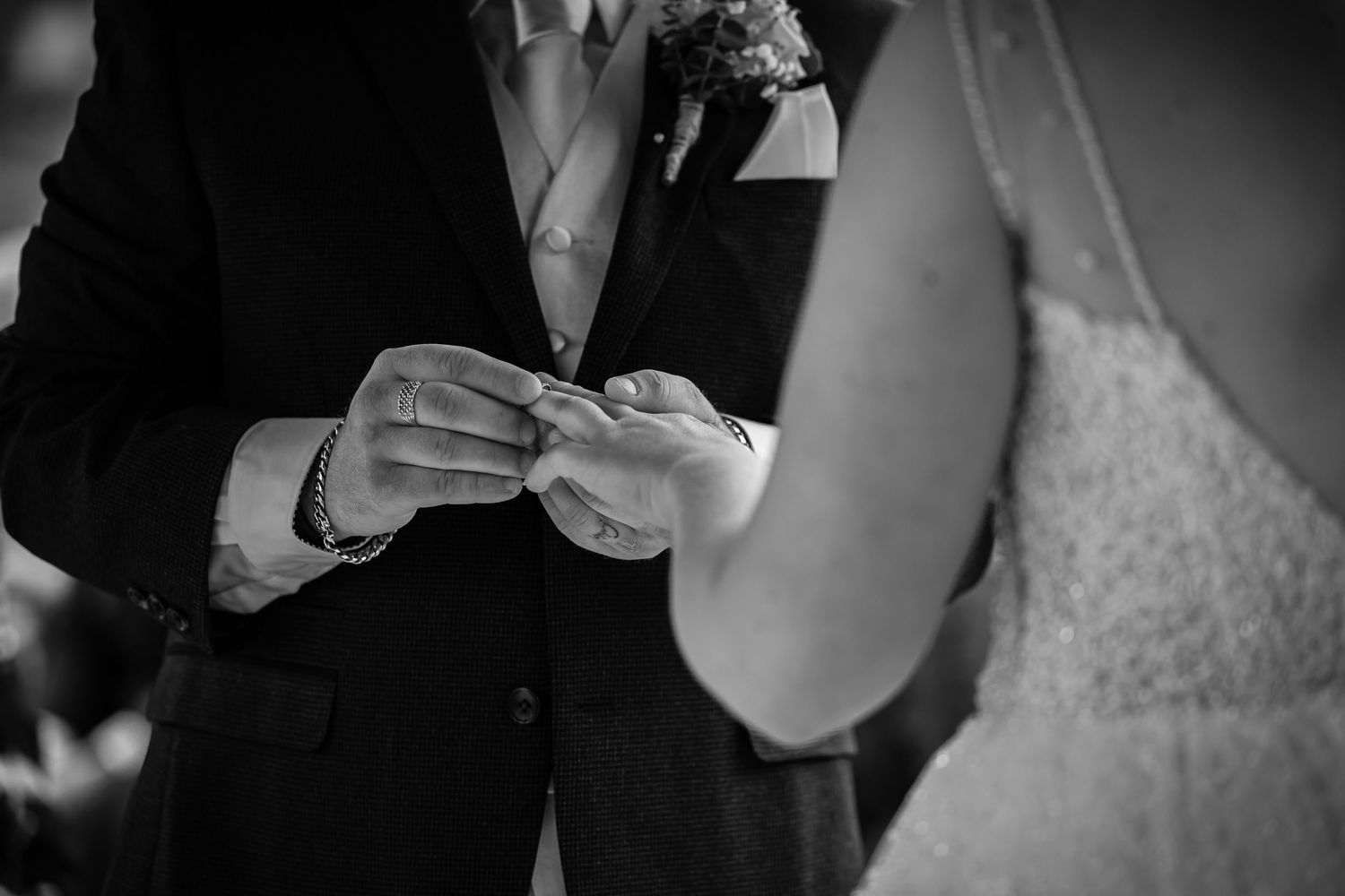 Black and white photo of wedding ring exchange during ceremony.