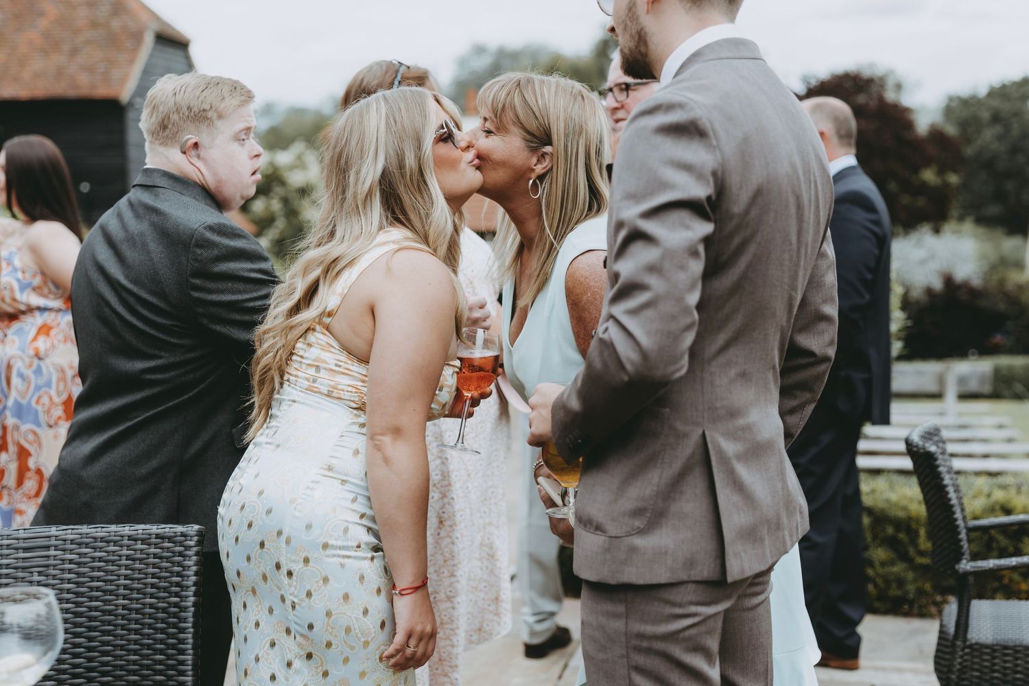 Guests in formal attire socialize during an outdoor summer wedding reception.