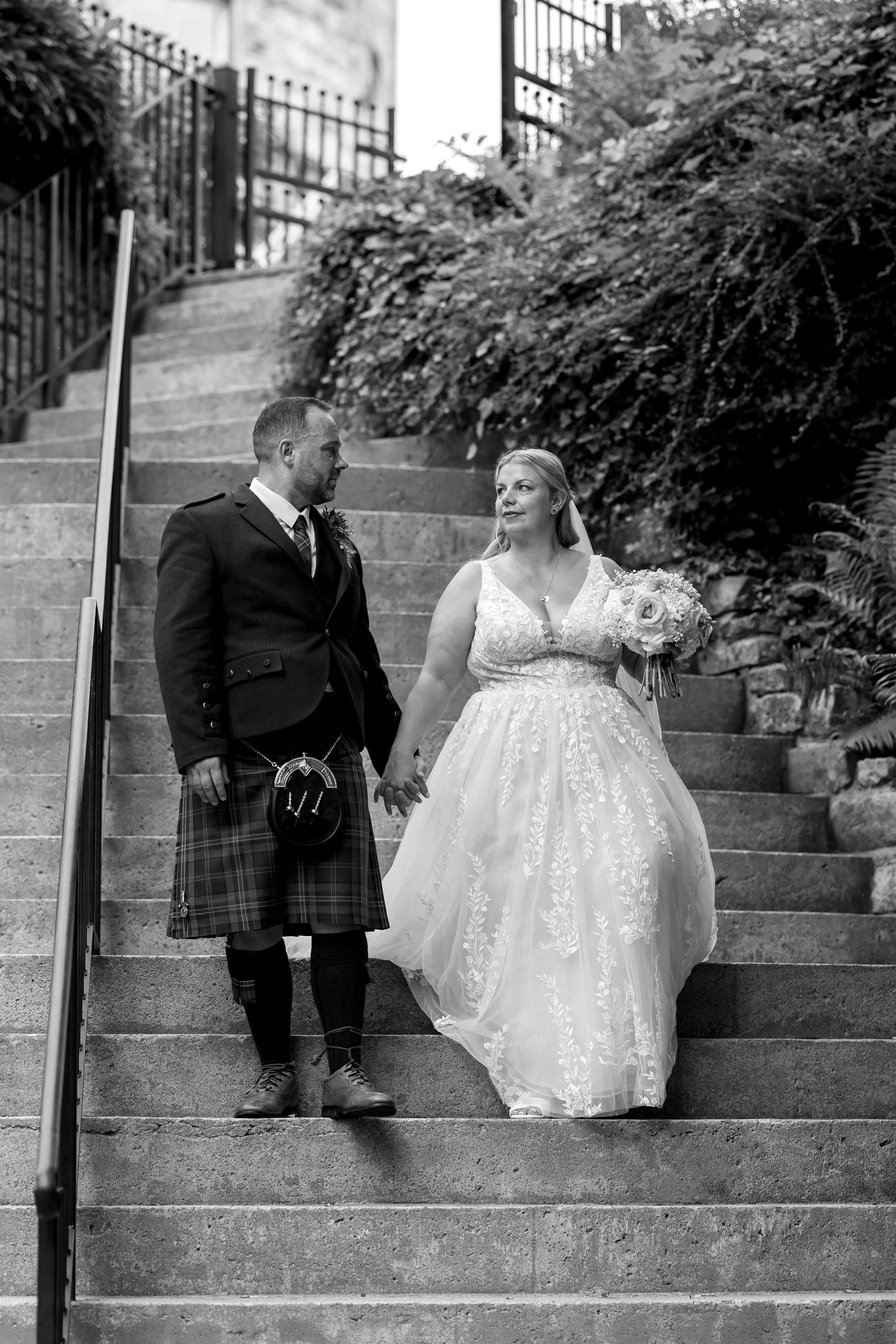 Black and white wedding portraits showing playful interactions on stone steps.