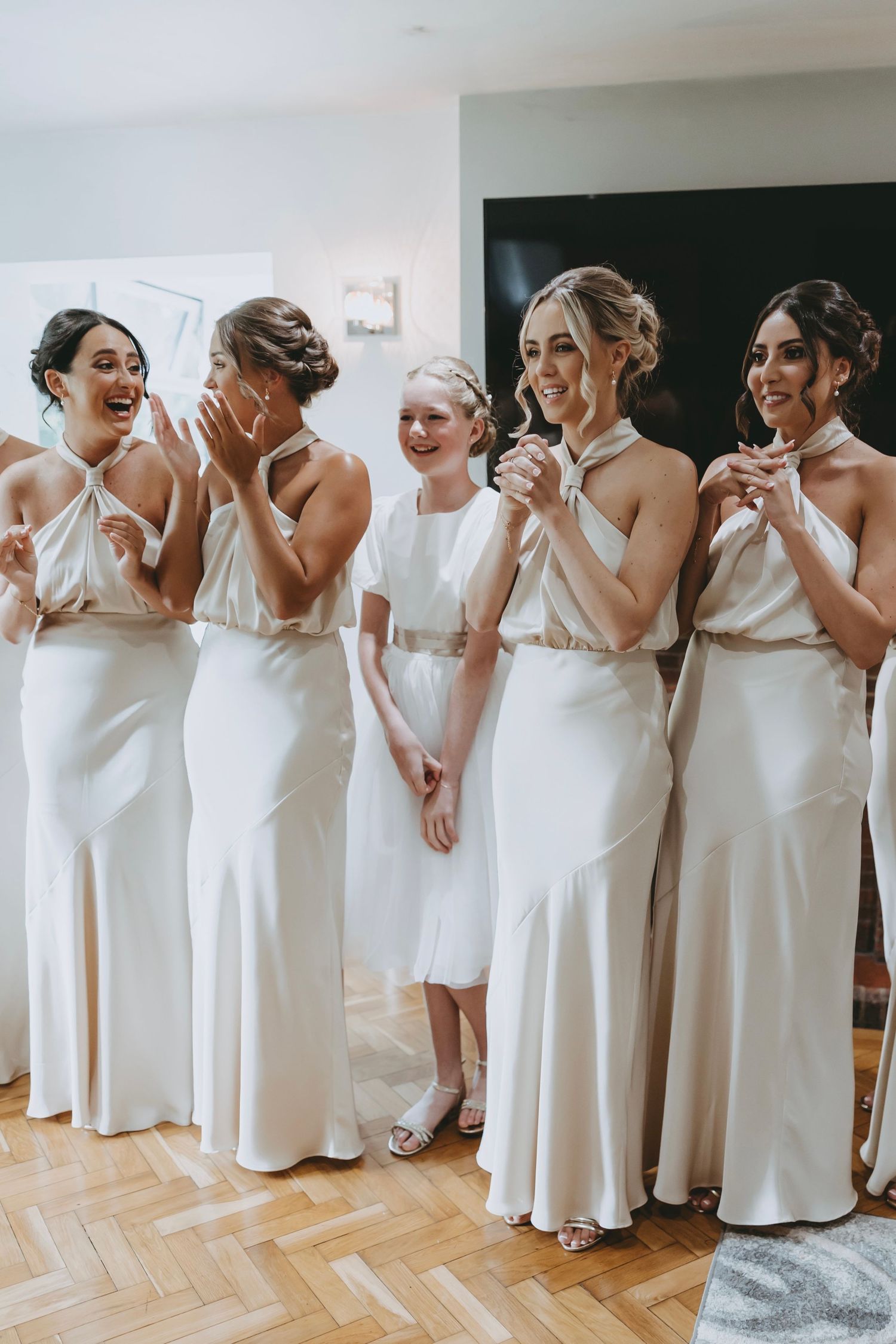 Candid moments of bridesmaids in matching white gowns showing joyful reactions.