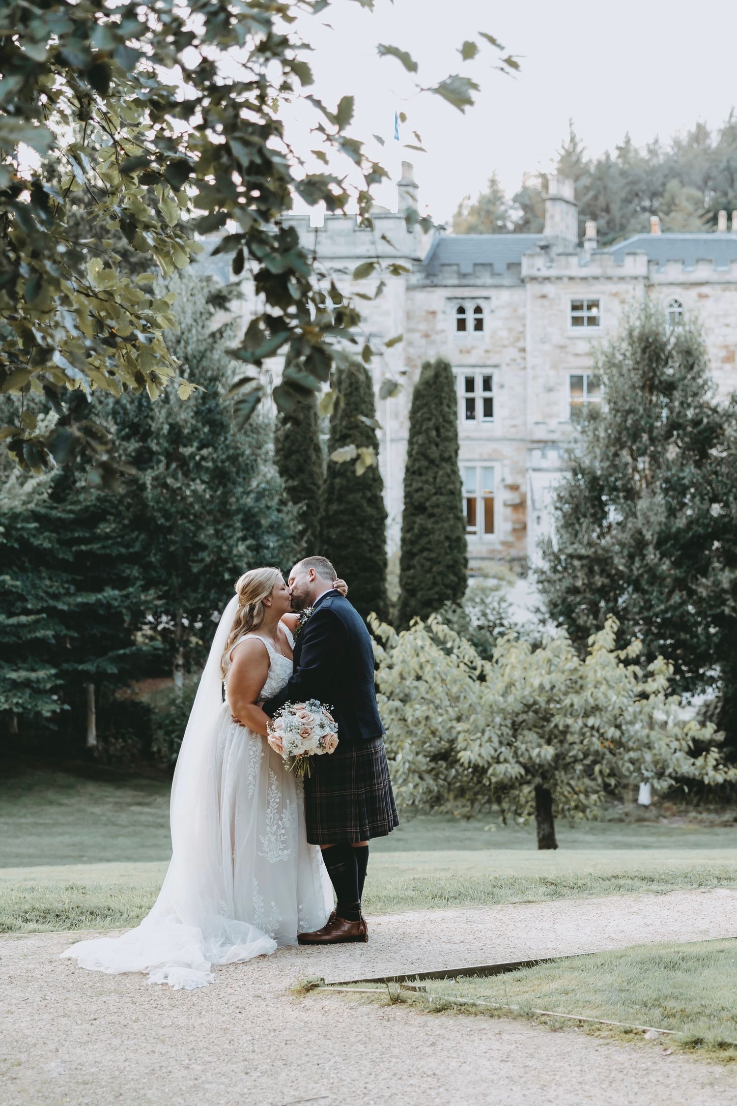 Romantic wedding portraits on manicured grounds with elegant estate building in background.