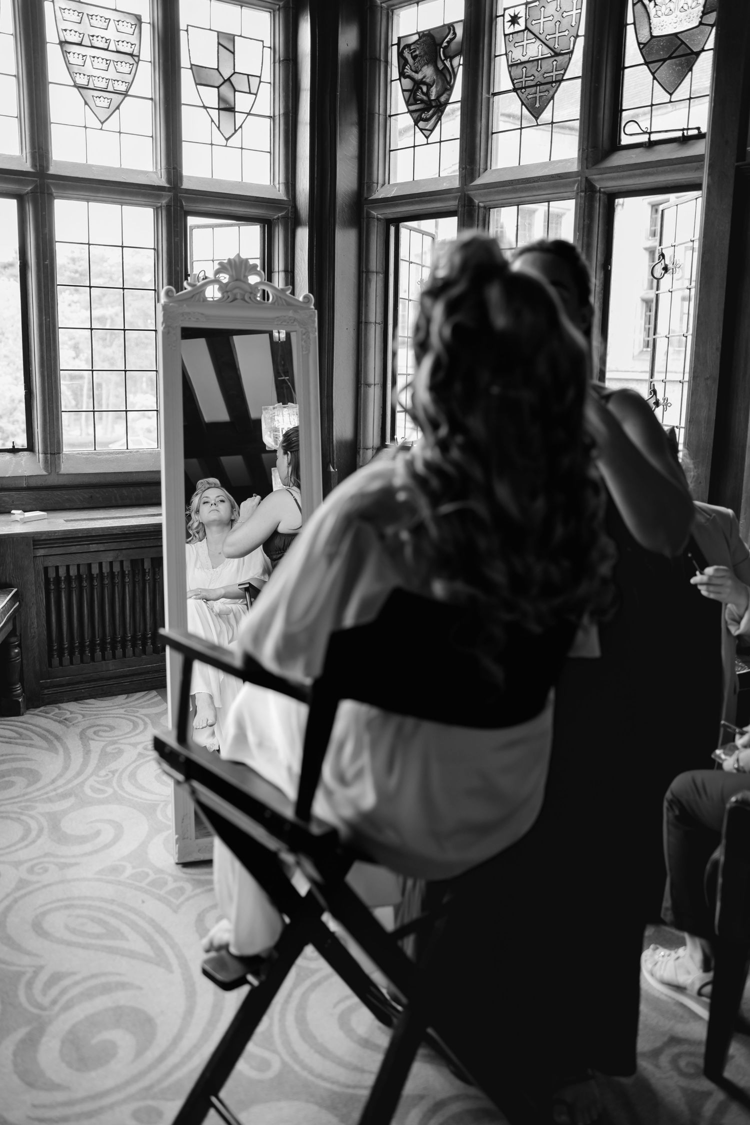Wedding preparation scene in room with decorative windows and director-style chairs.