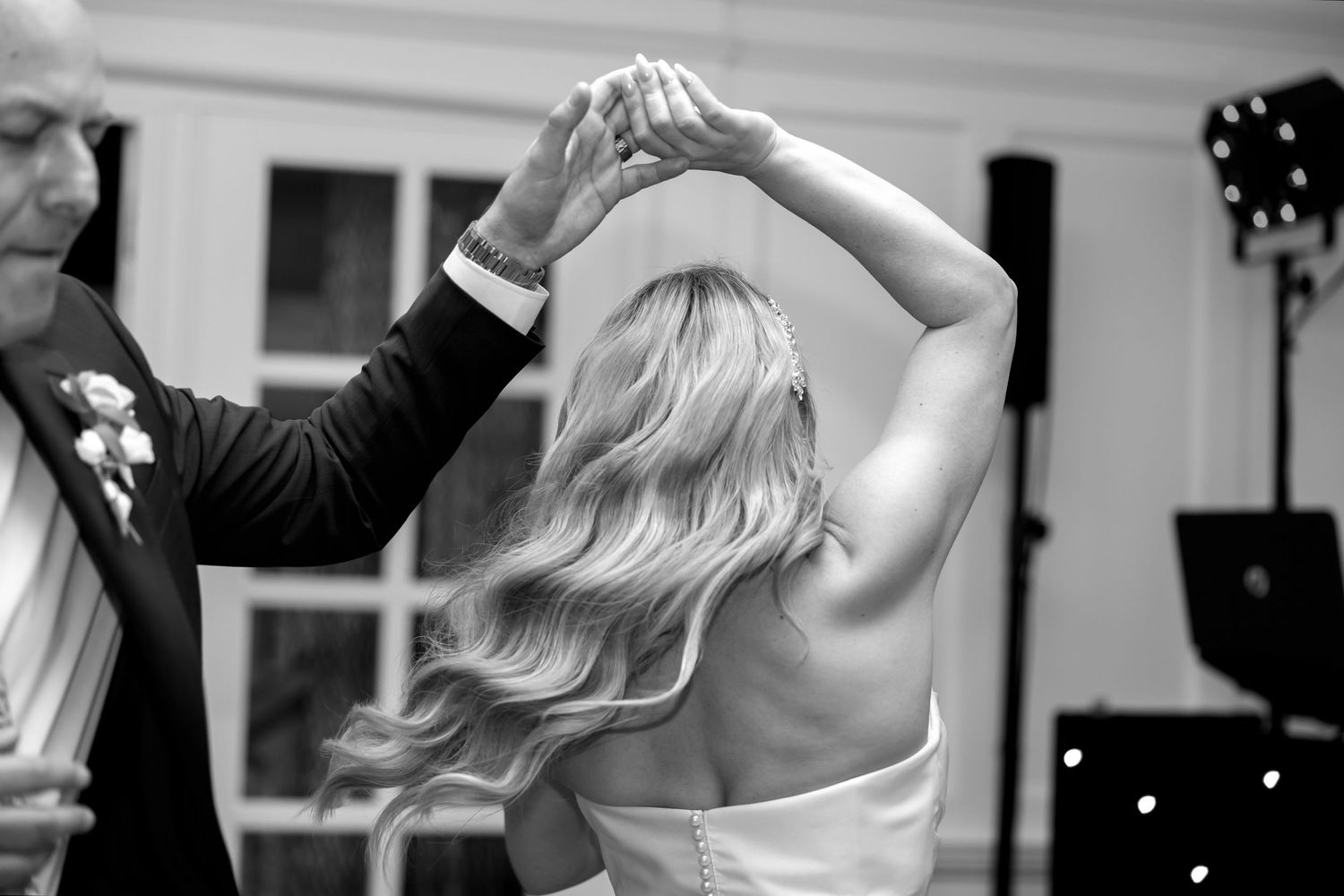 Couples dancing romantically in black and white at an indoor wedding reception.