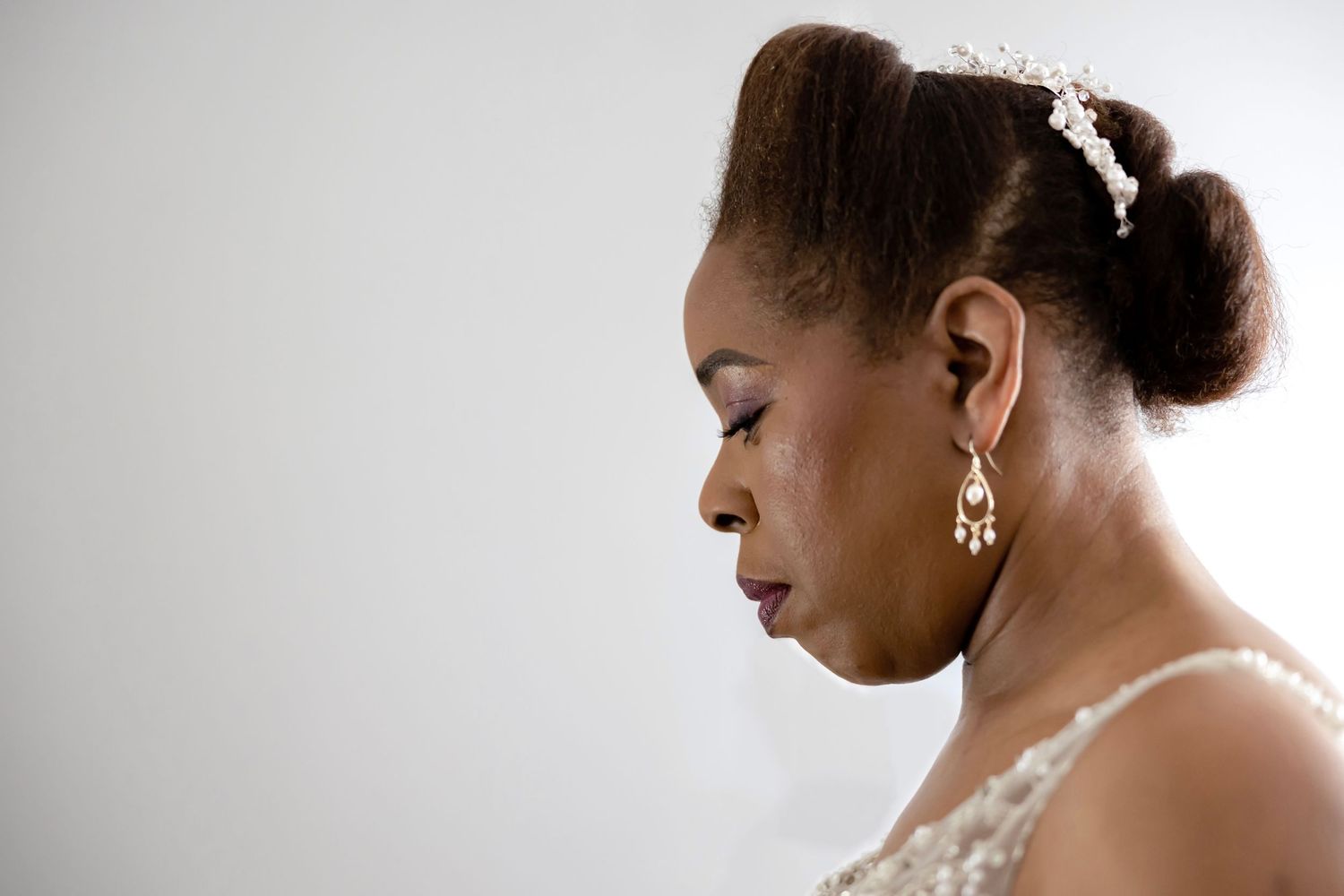 Elegant bridal portrait showing jewelry and hair accessories against white background.