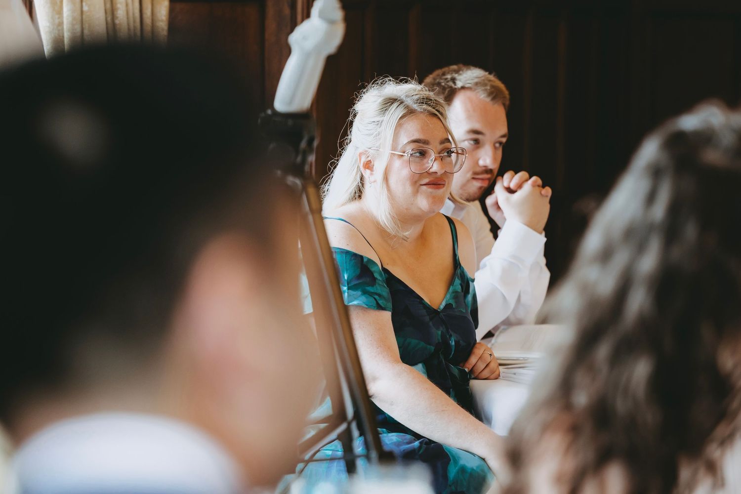Wedding guests raise glasses during a toast at an elegant indoor reception.