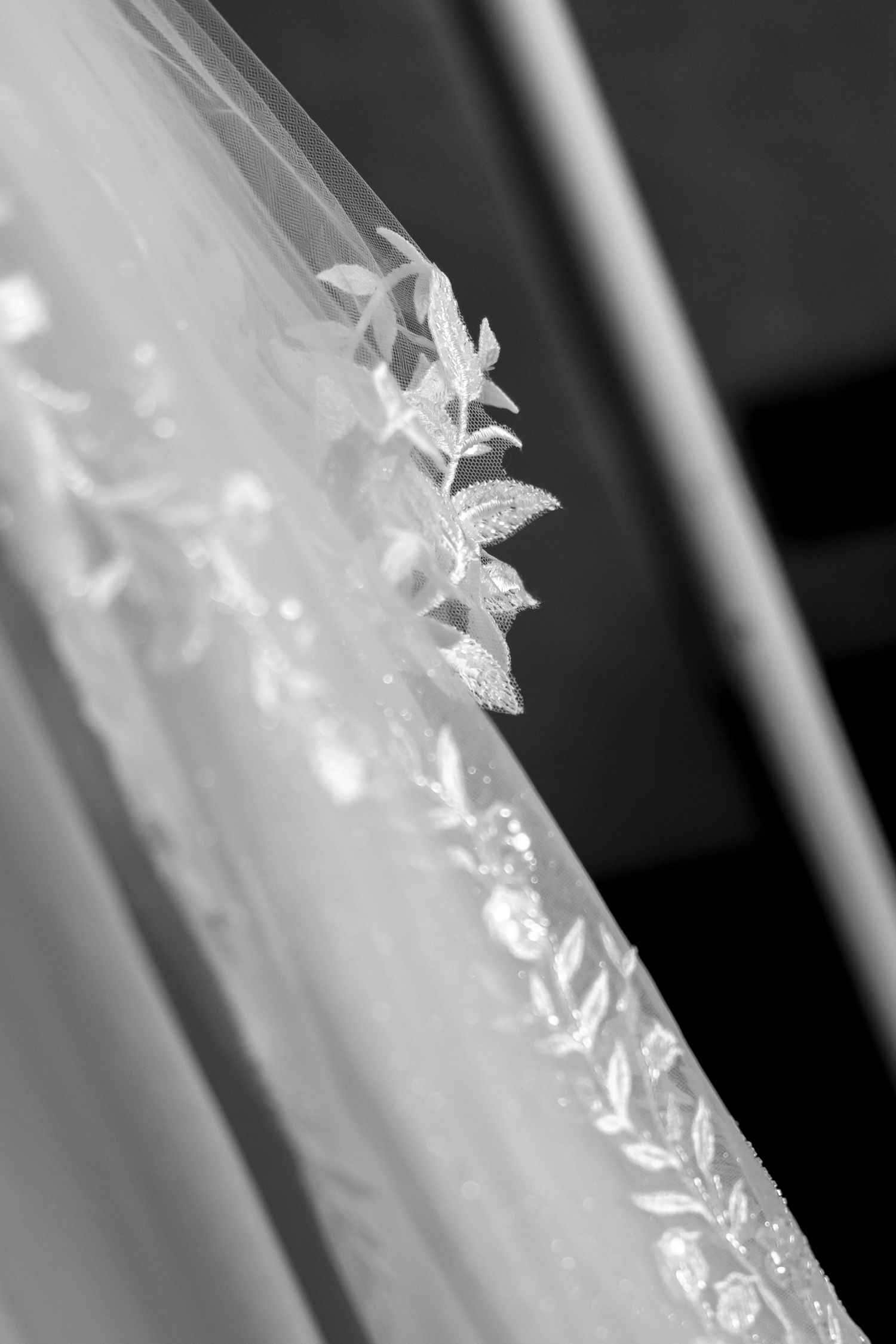 Close-up detail of delicate white lace embroidery on wedding dress fabric.