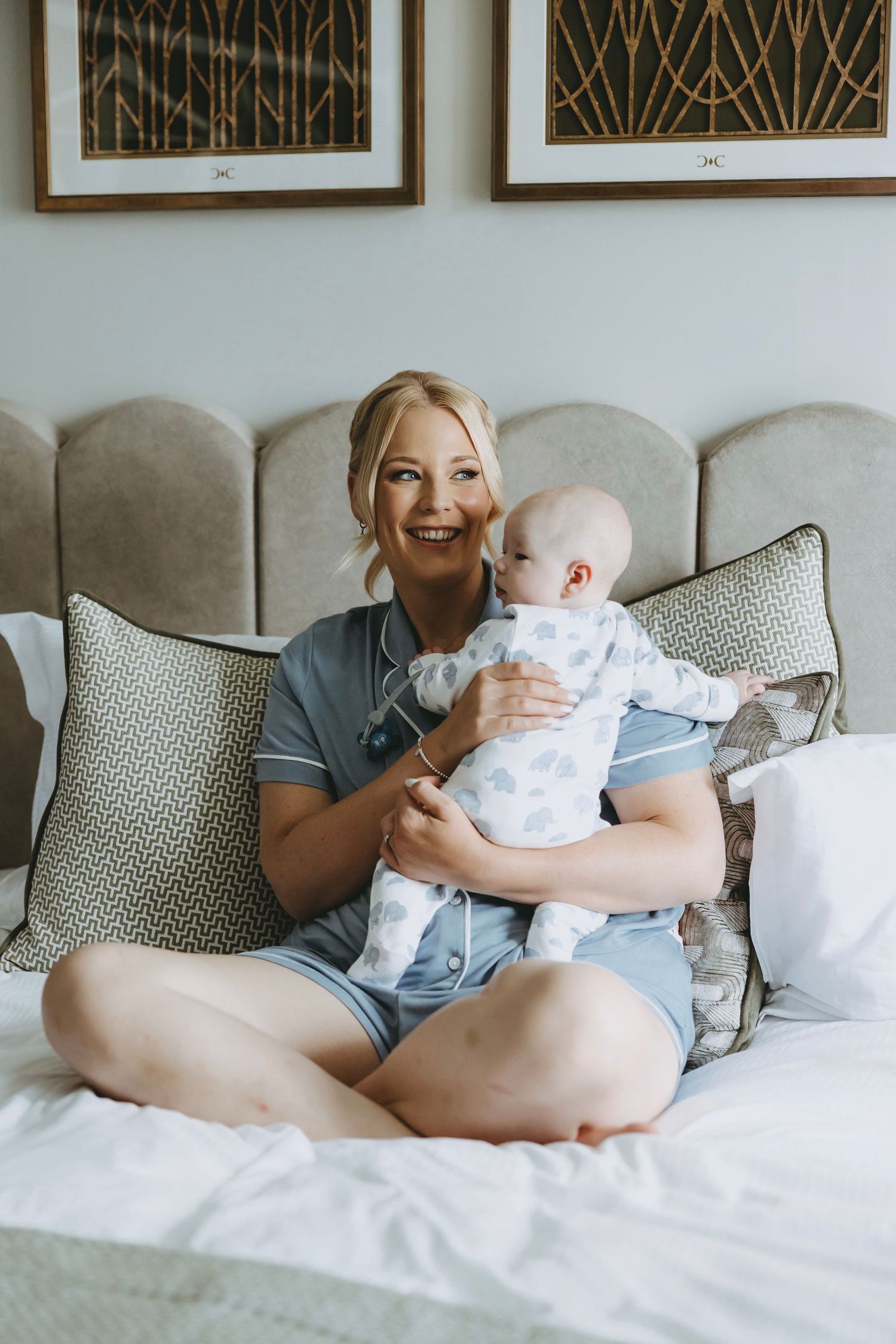 Adult and baby sharing joyful moments while relaxing on a bed with decorative pillows.