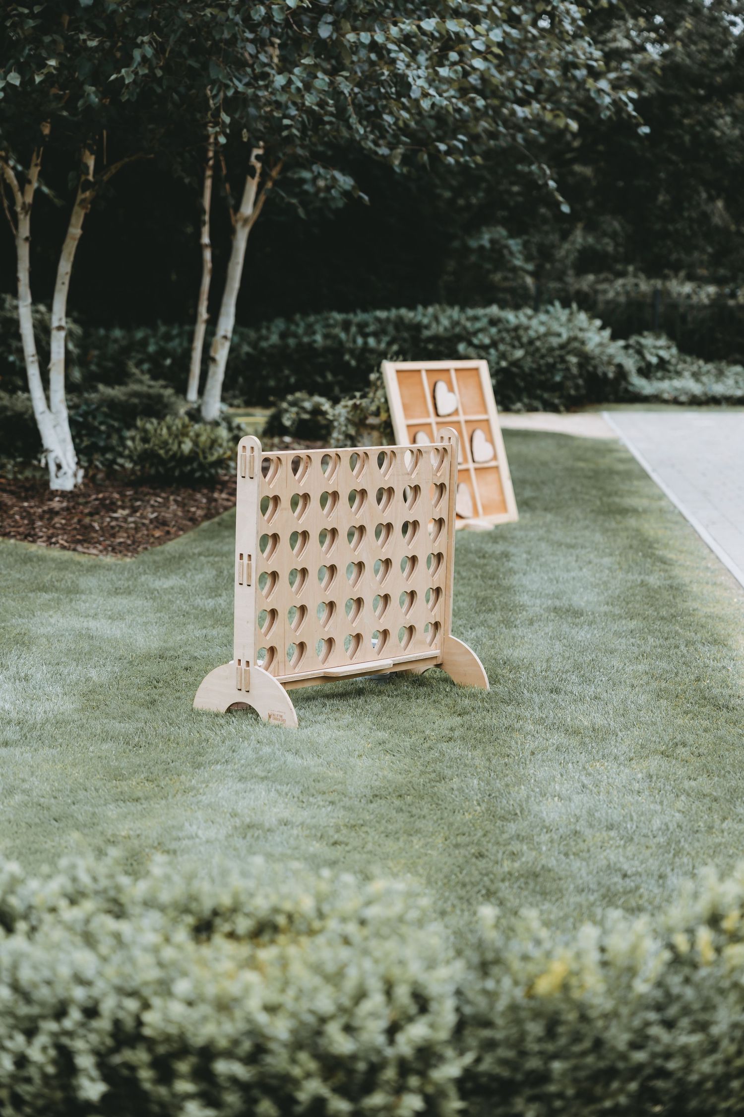 Wooden Connect Four game set up on grass for outdoor wedding entertainment.