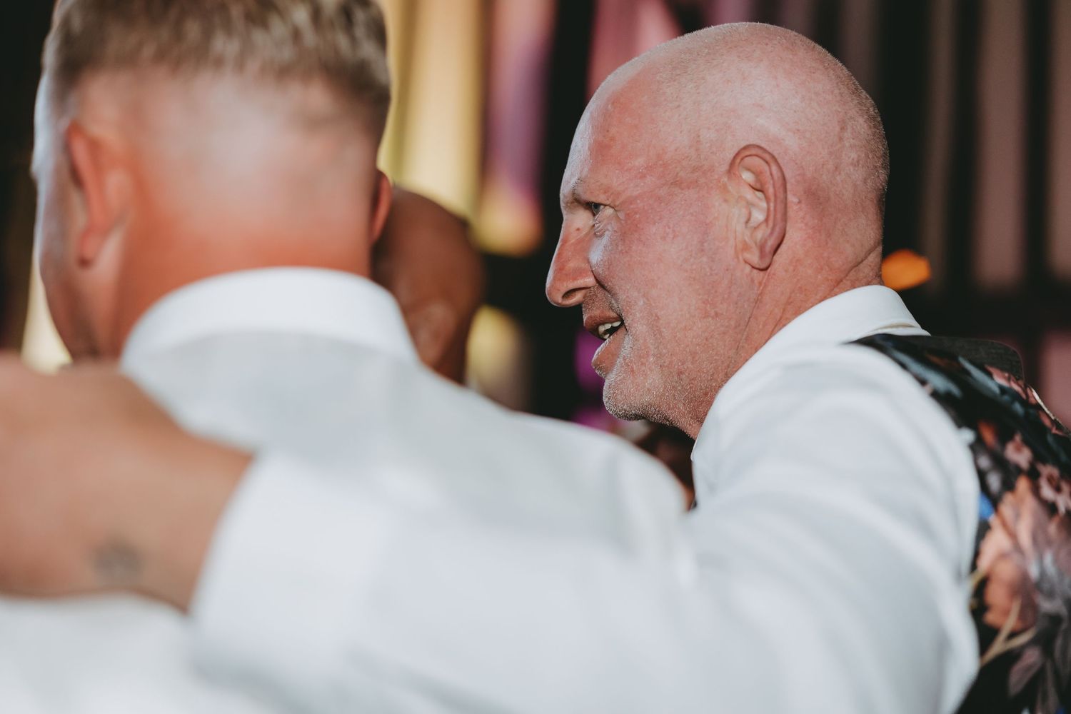 Wedding guests dancing and laughing together during an evening celebration.