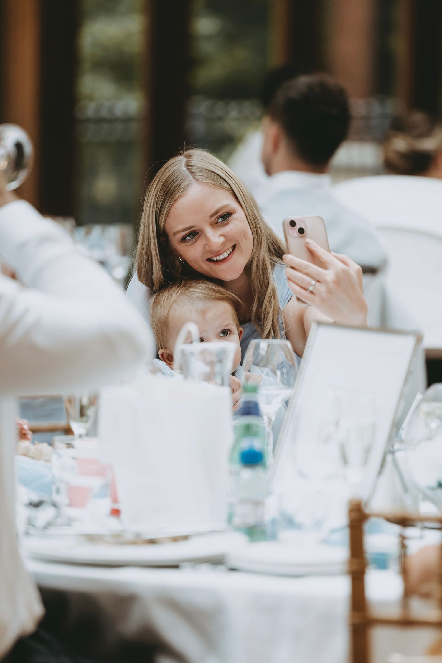 Guests seated at round tables with white linens during an indoor celebration.