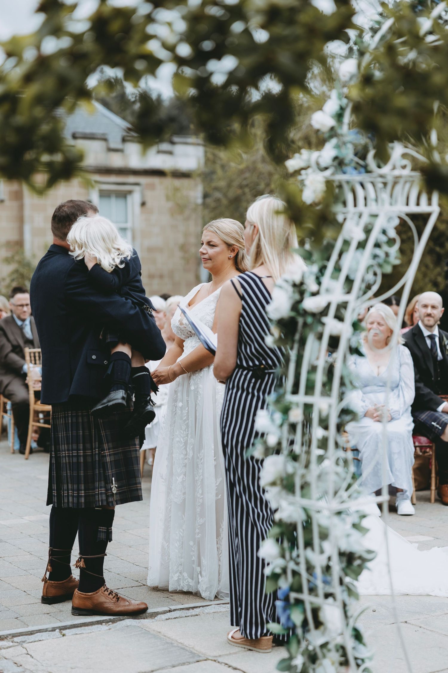 Scottish wedding ceremony with traditional kilts and striped attire.