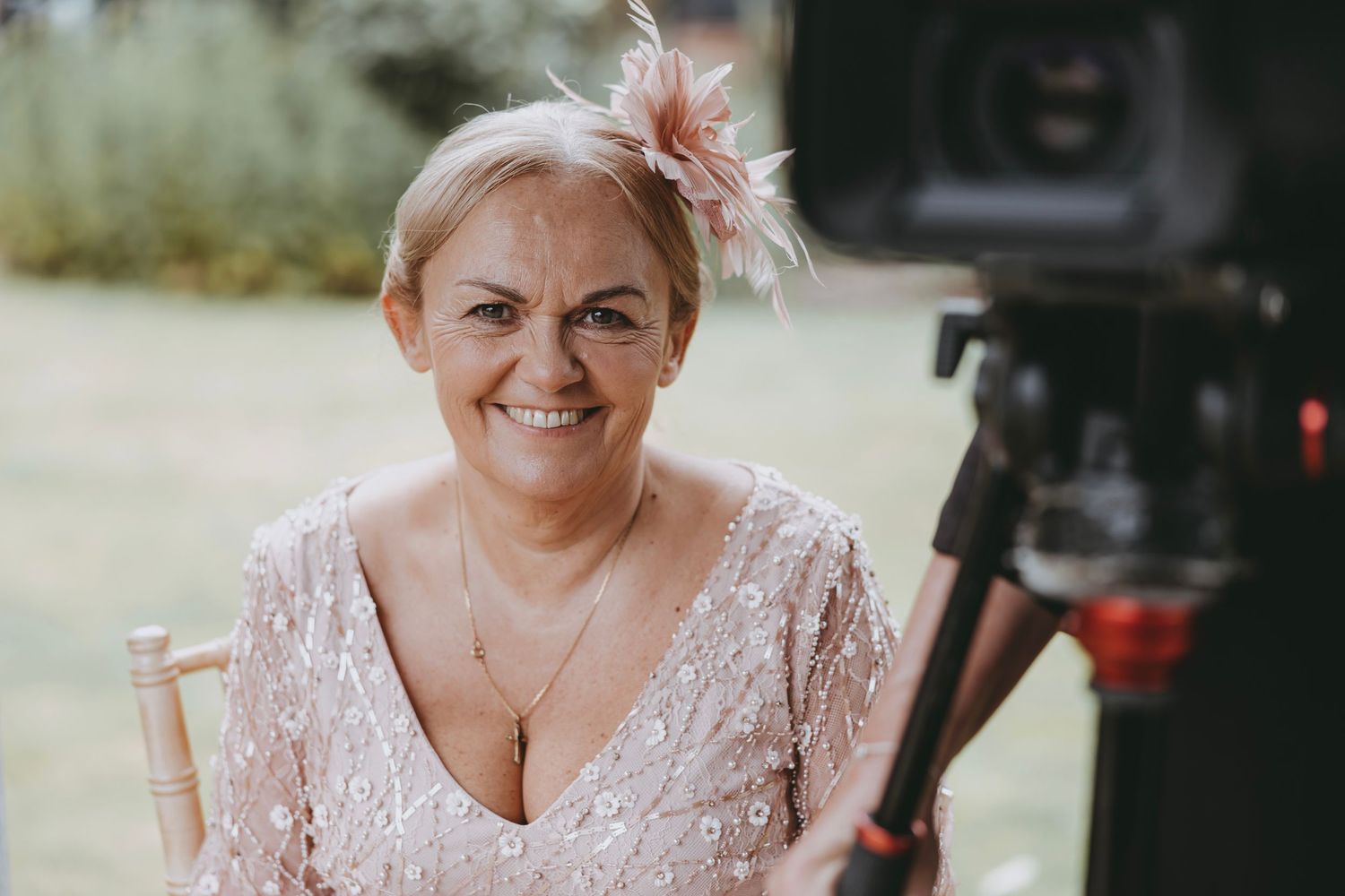 Wedding attendee wearing a pink lace dress at an outdoor celebration.