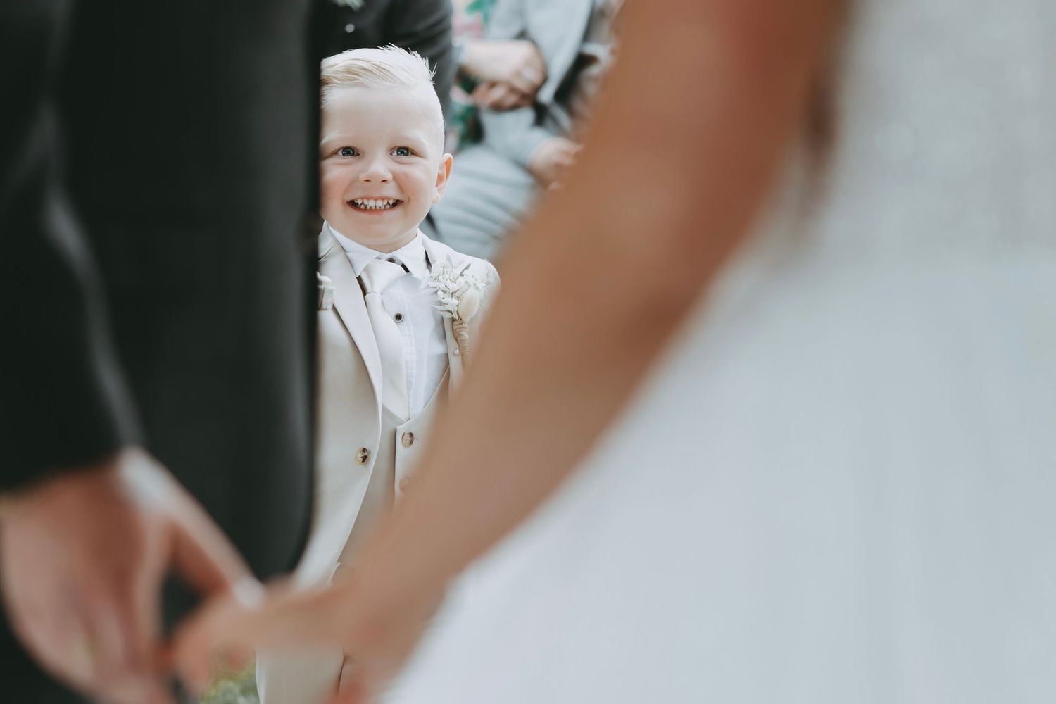 Intimate moment during wedding ring exchange with guests looking on.