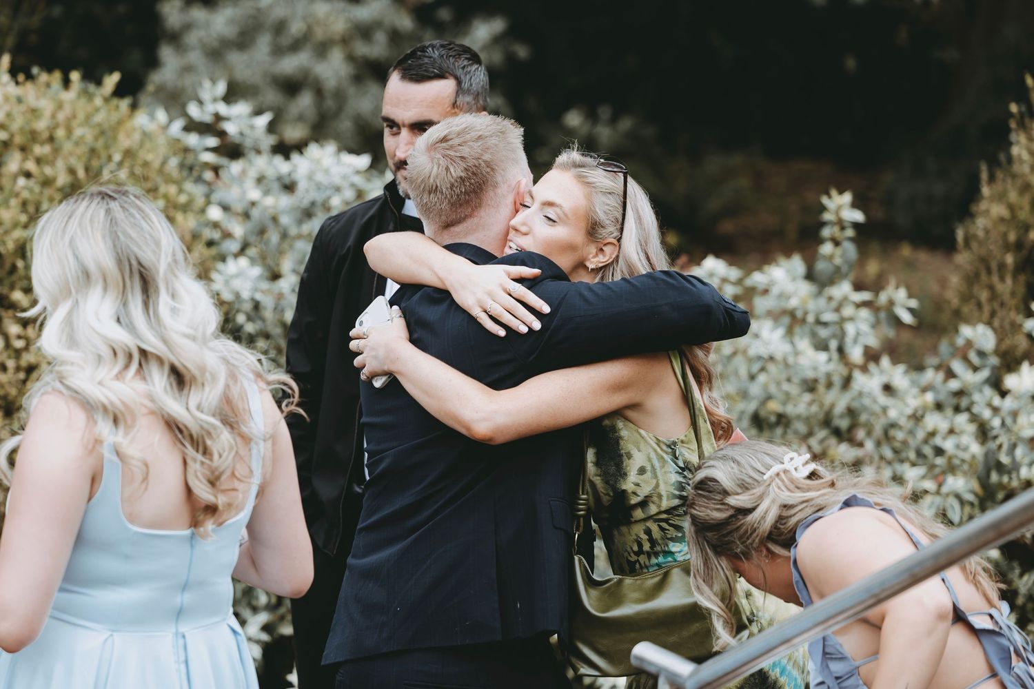 Emotional moments captured during an outdoor wedding ceremony with guests looking on.
