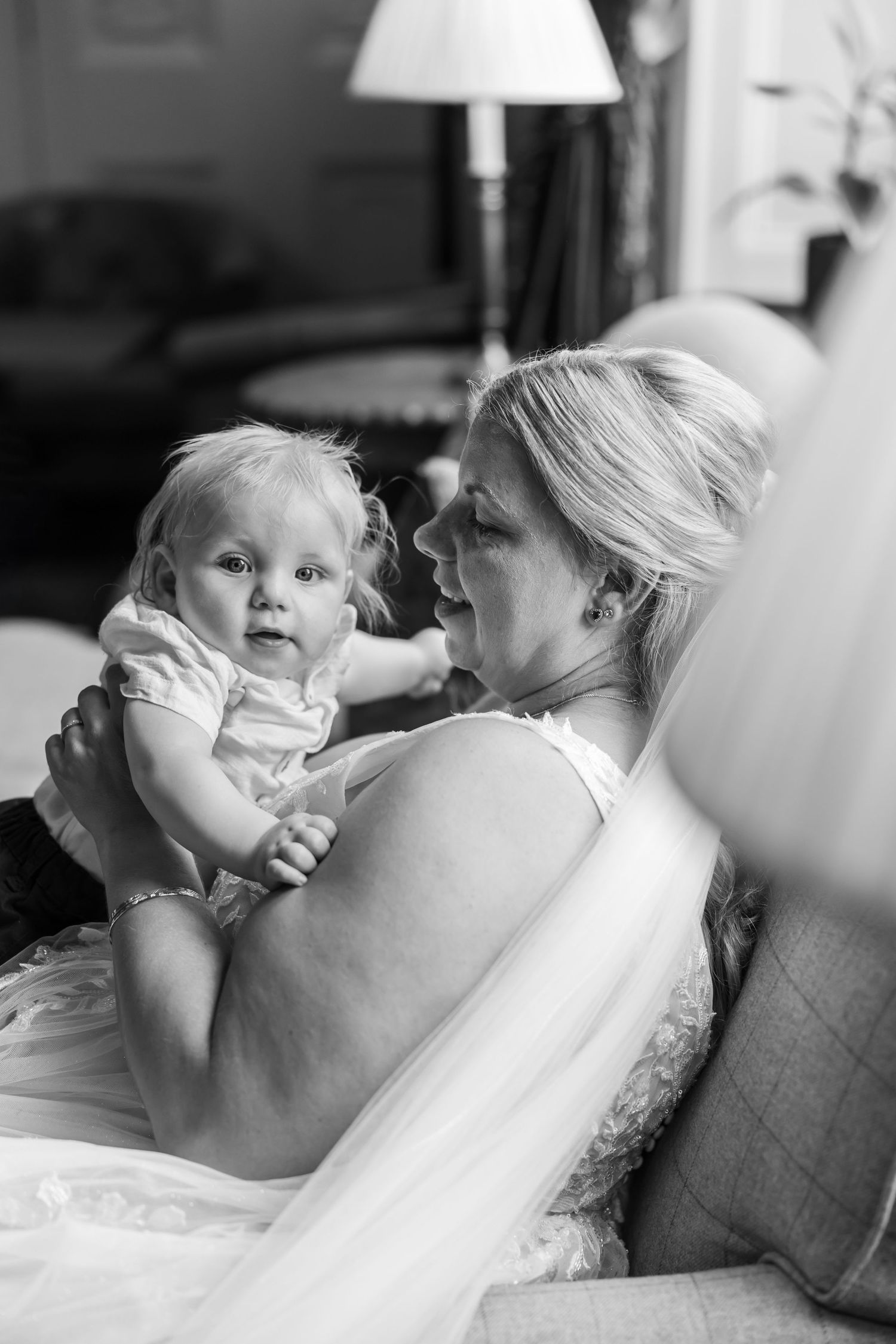 Black and white photo capturing an emotional moment between a bride and baby during a wedding day.