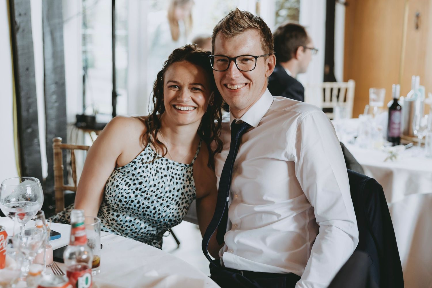Wedding guests share laughter and conversation during an elegant indoor reception.