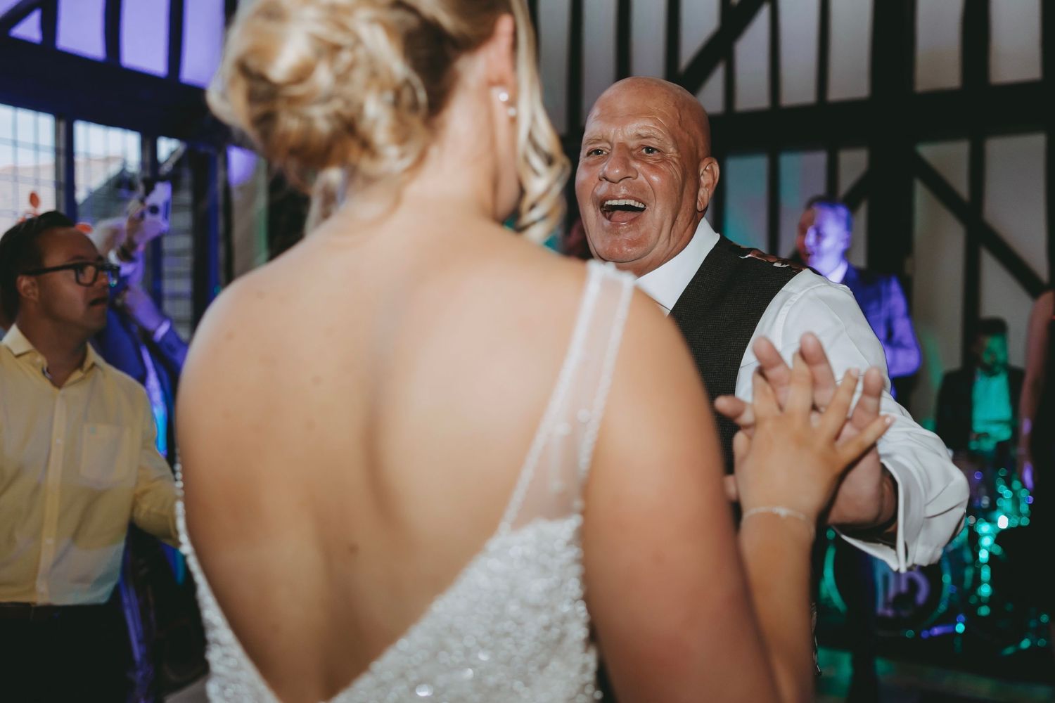 Guests enjoying themselves on a lively dance floor at an indoor wedding reception venue.
