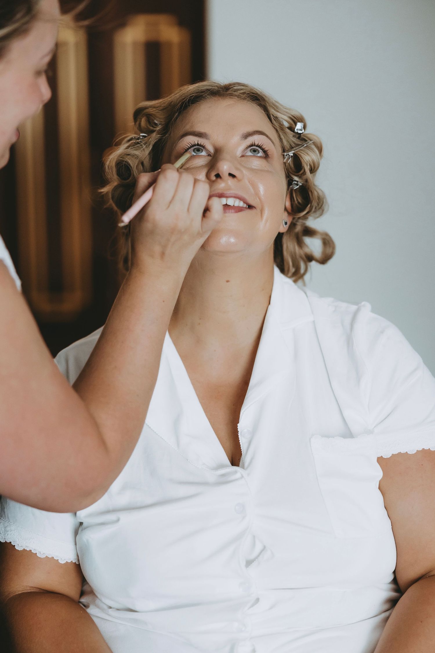Person having makeup applied while wearing a white top.