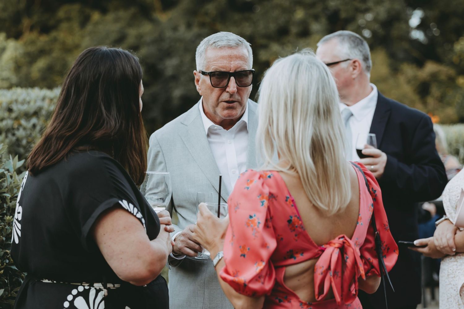 Wedding guests mingle and socialize during an outdoor reception gathering.
