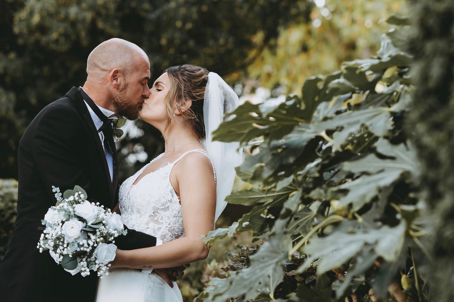 Romantic outdoor wedding portraits among green foliage.