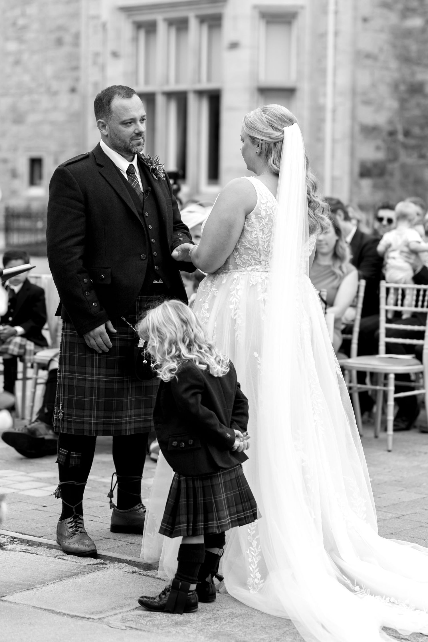 Black and white photo of wedding ceremony with Scottish kilts and white bridal gown.