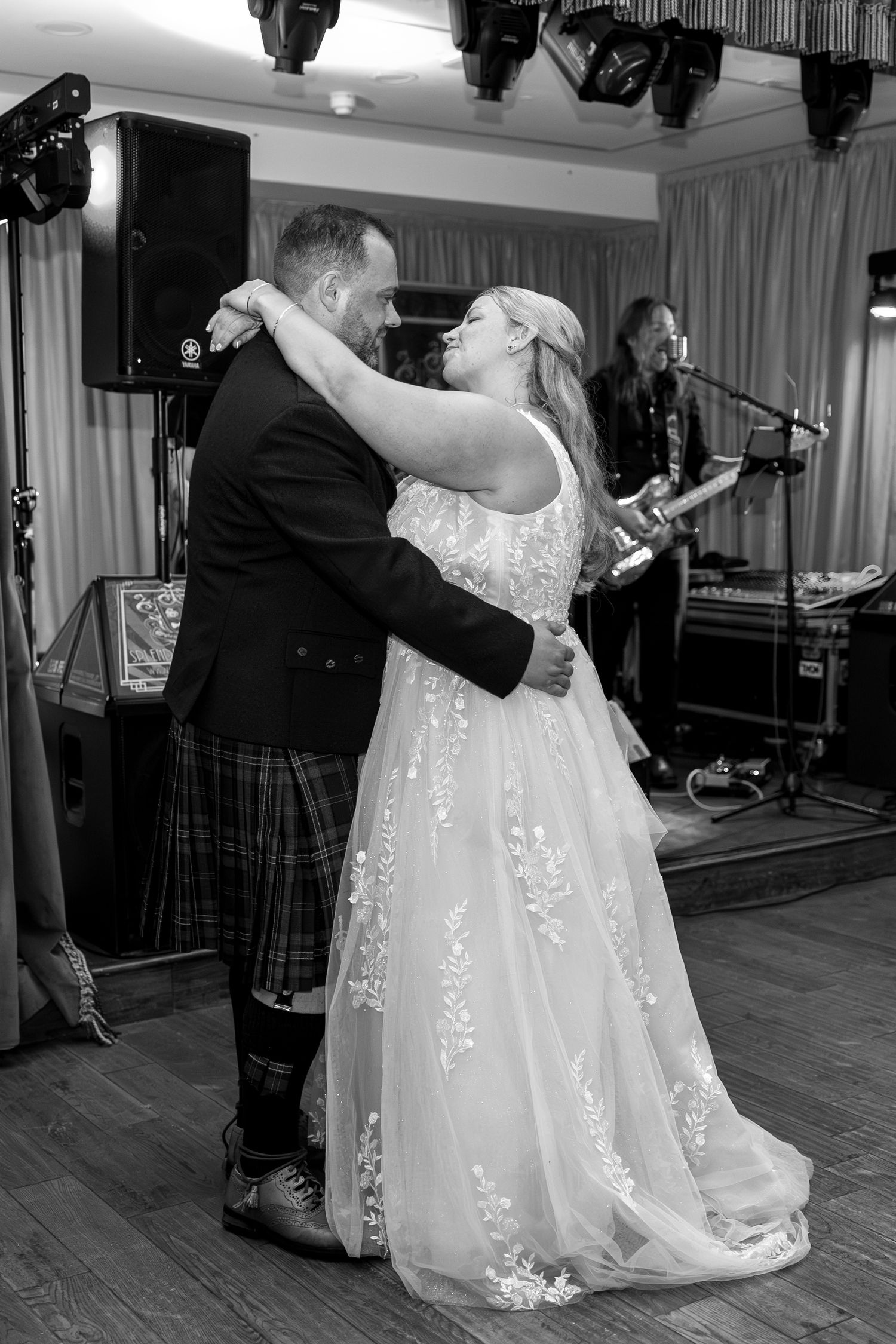 Newlyweds dance together on a wooden dance floor at their wedding reception.