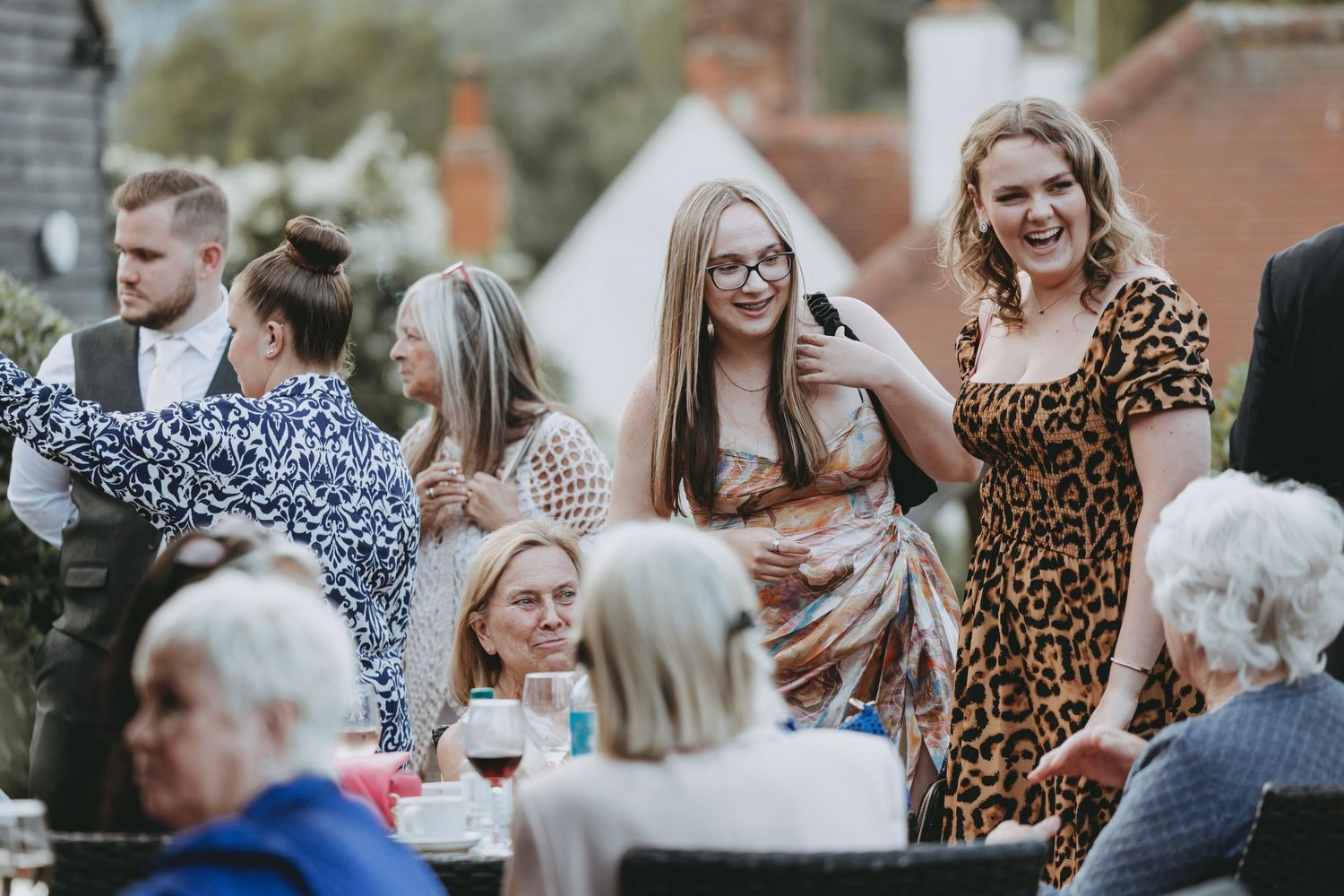 Wedding guests in colorful attire socializing at outdoor reception.