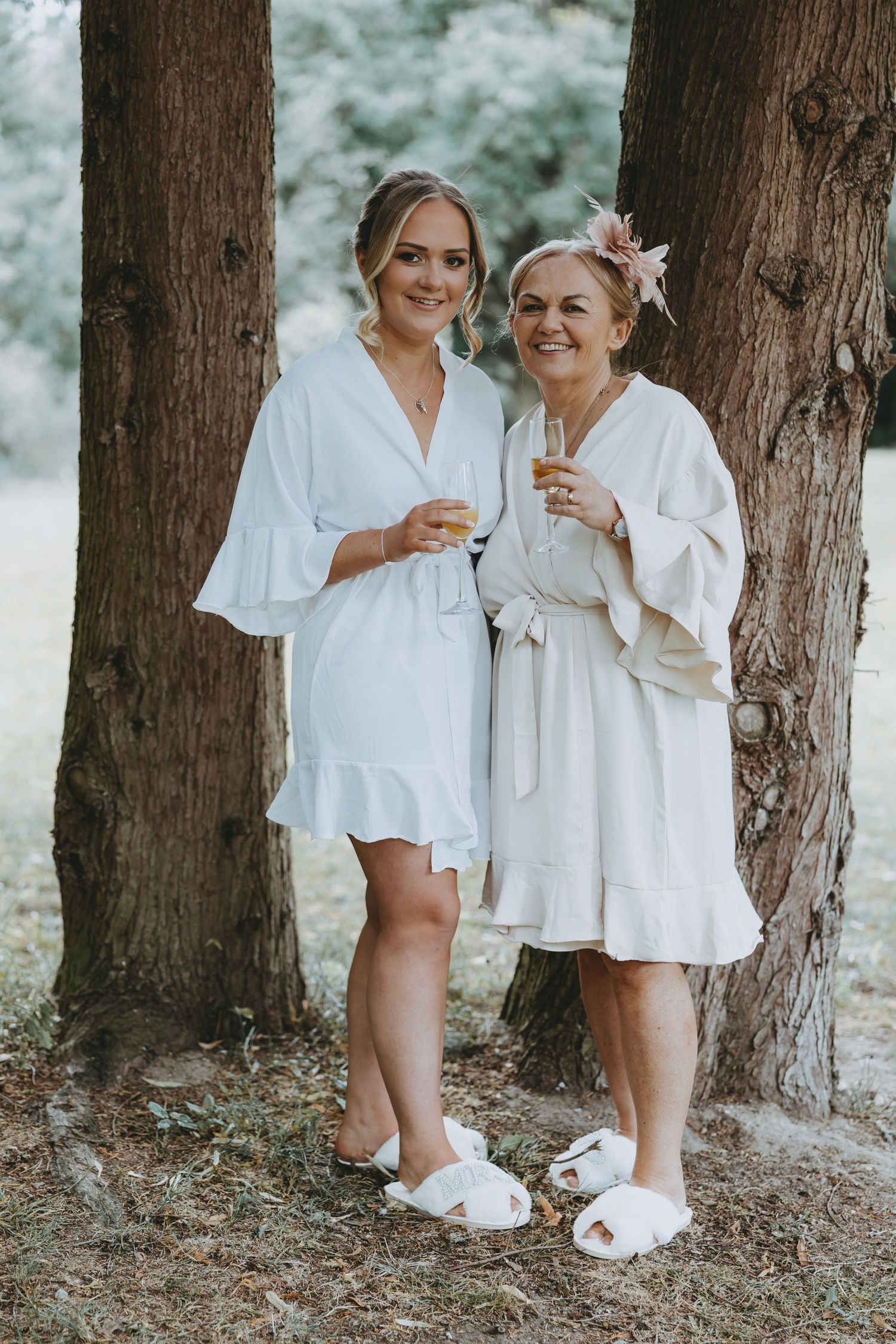 Close-up view of people in white robes and slippers standing together by a tree trunk.