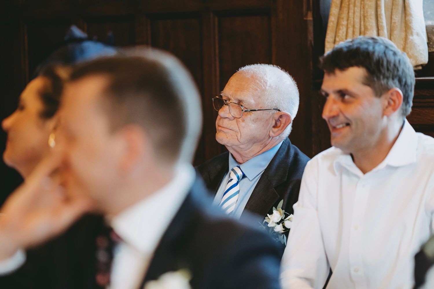 Row of formally dressed wedding guests seated at reception tables.