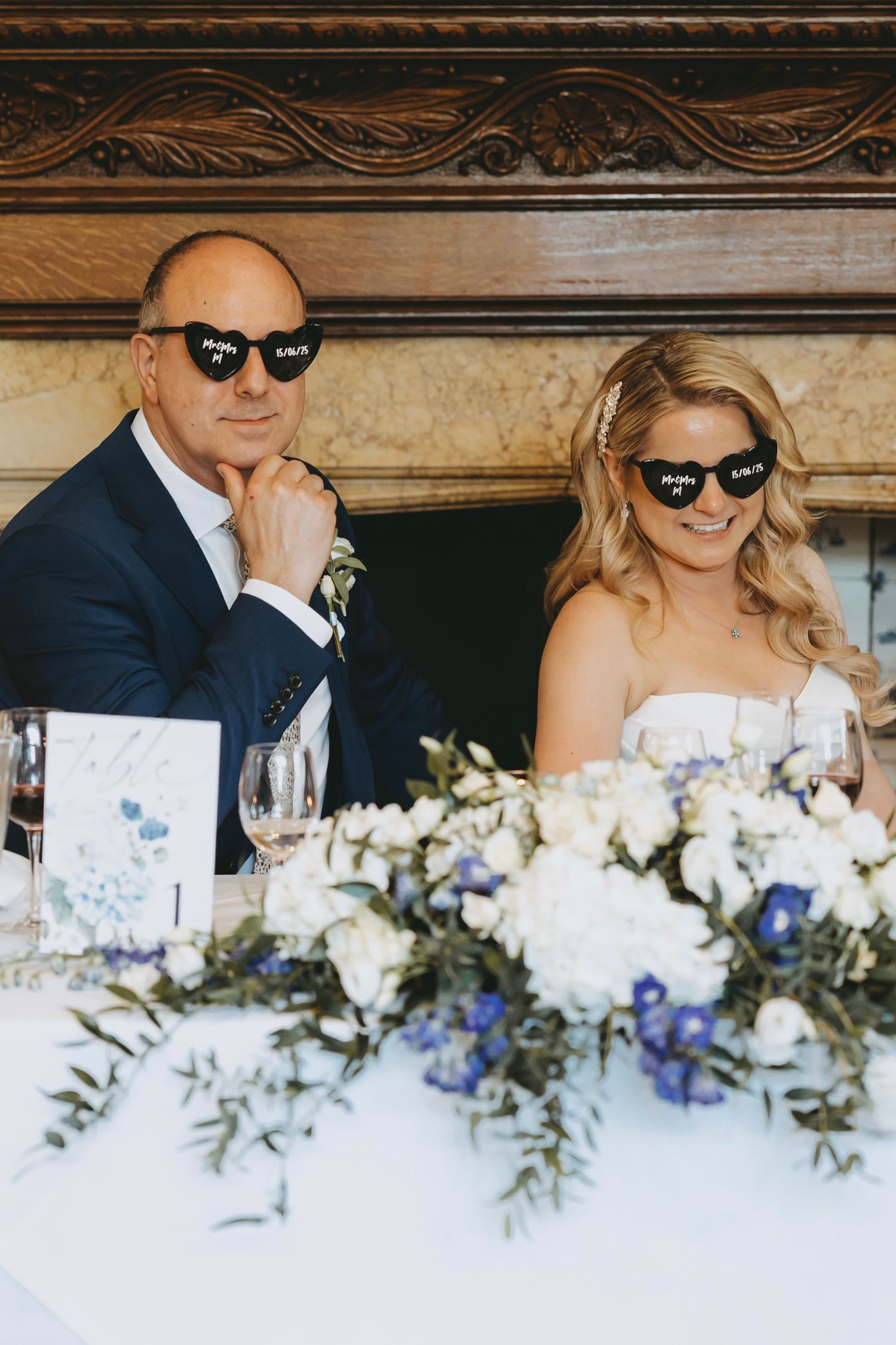 Wedding party wearing sunglasses at reception table decorated with white and blue flowers.