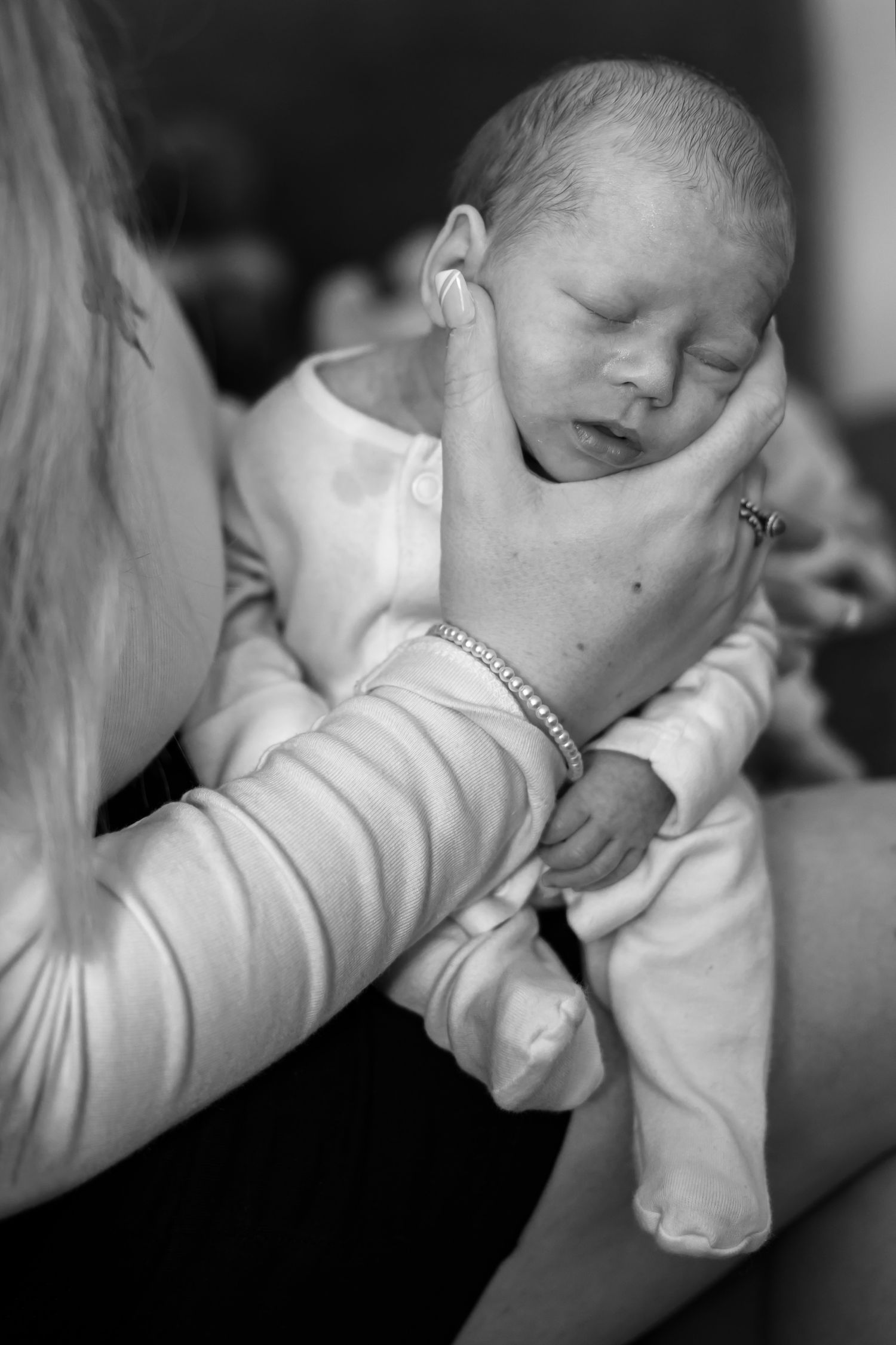 Black and white sequence of a baby sleeping peacefully in white clothing, shown from multiple angles.
