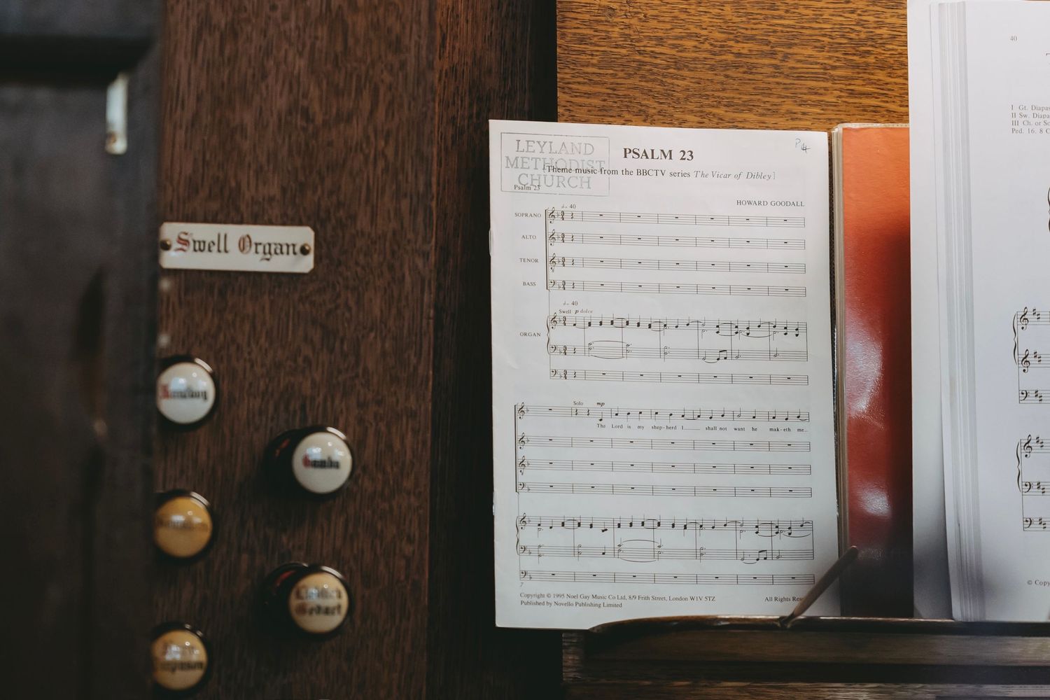 Sheet music displayed on an organ with stop knobs visible in the frame.