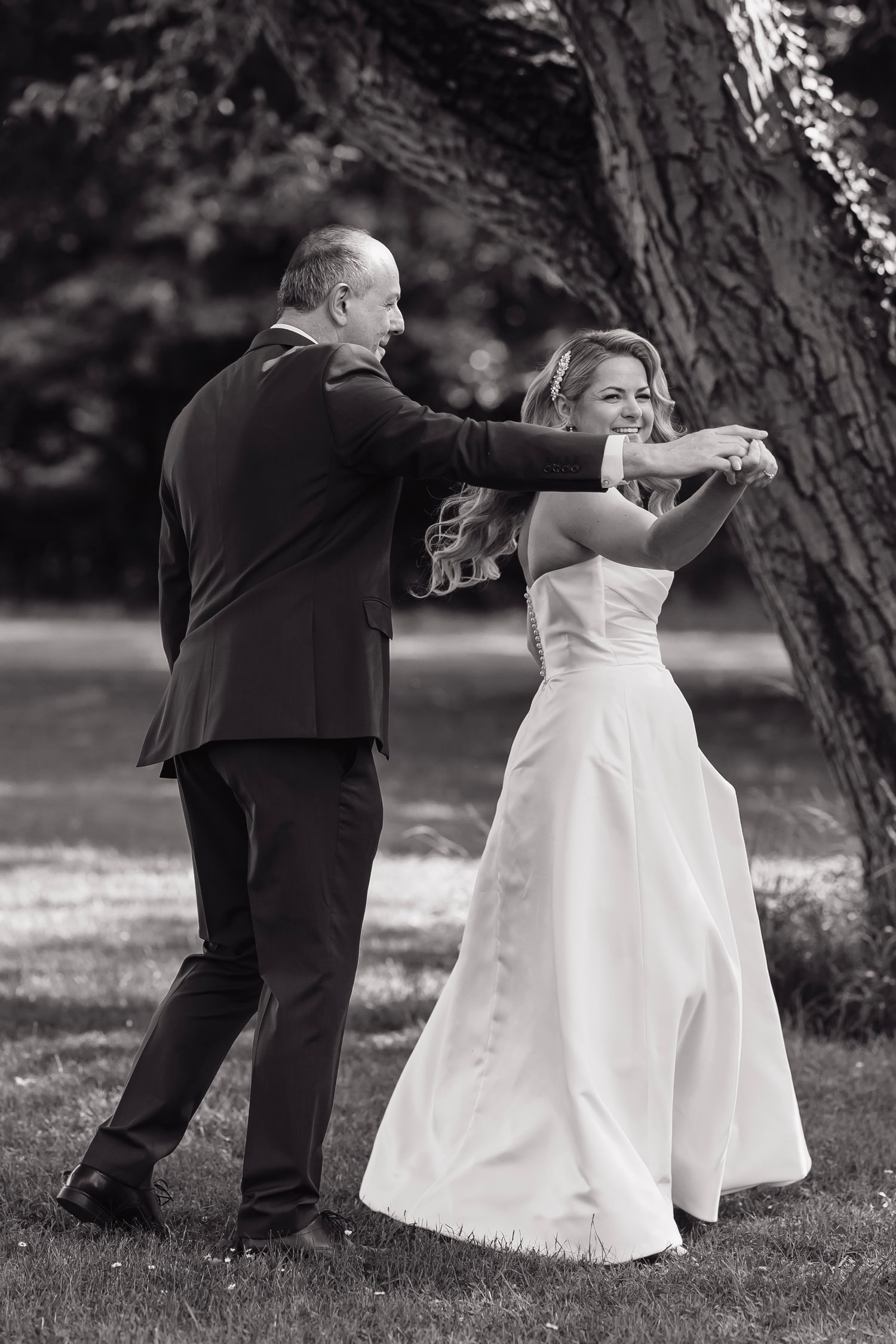 A black and white sequence showing playful moments between a couple on grassy grounds.