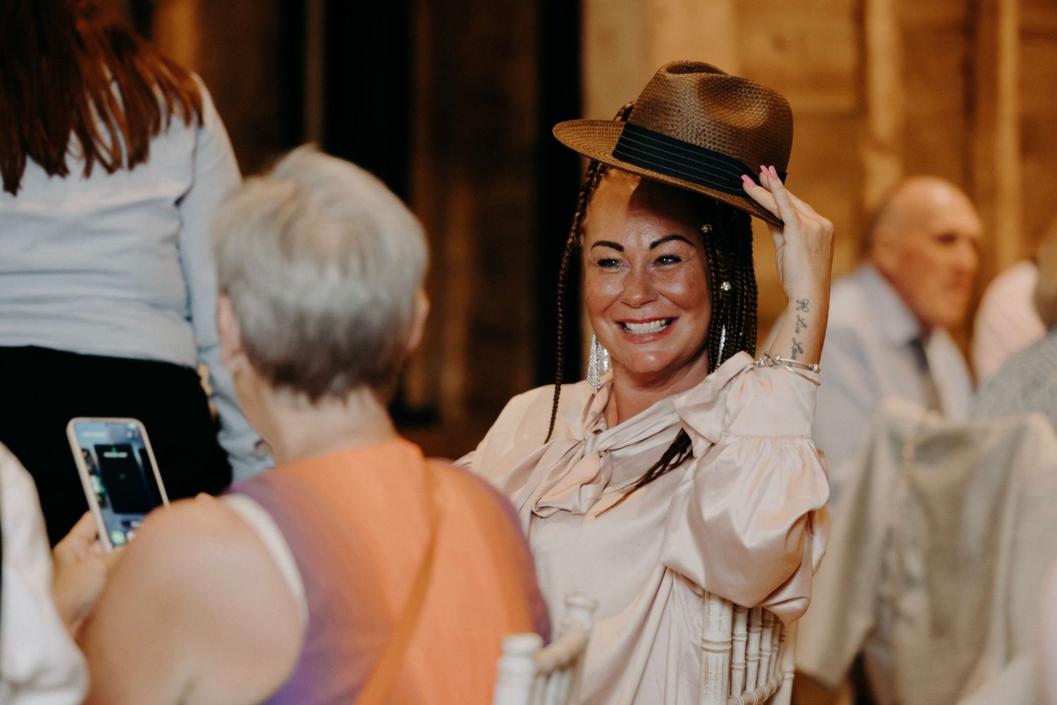 A group of people dancing and celebrating at a lively wedding reception party with warm lighting.