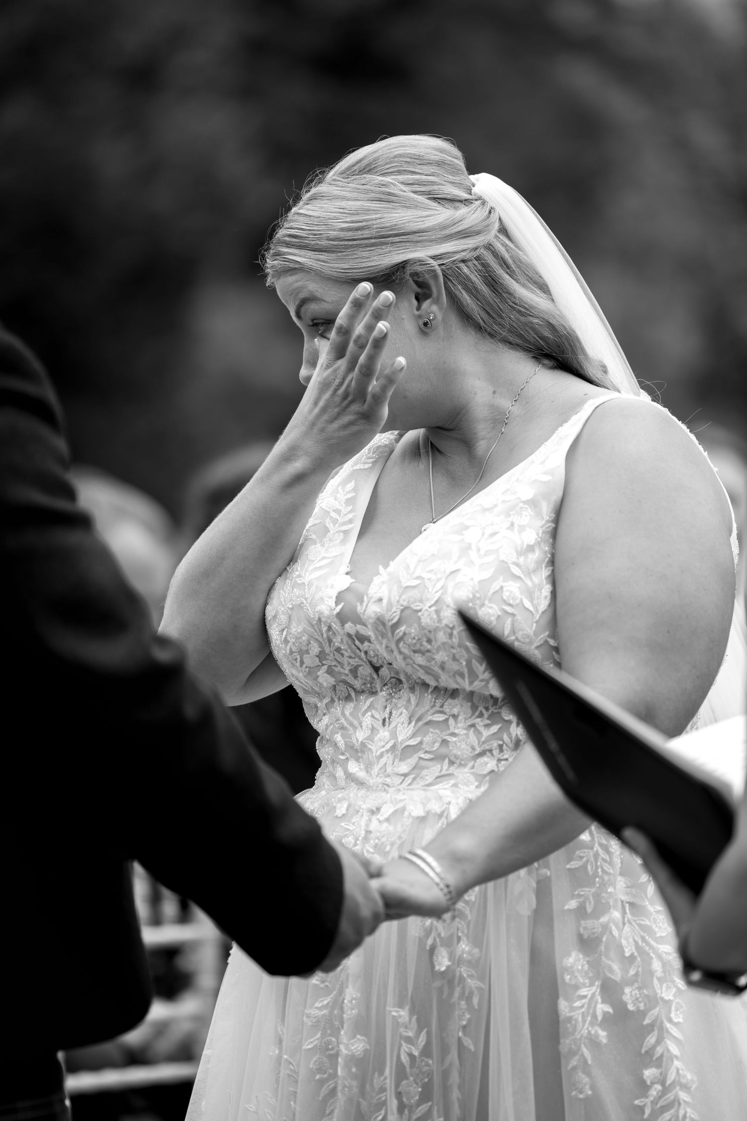 Black and white detail shot of a lace wedding dress during ceremony.