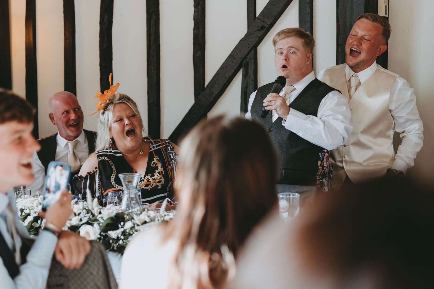 Wedding reception guests reacting with laughter to speeches.