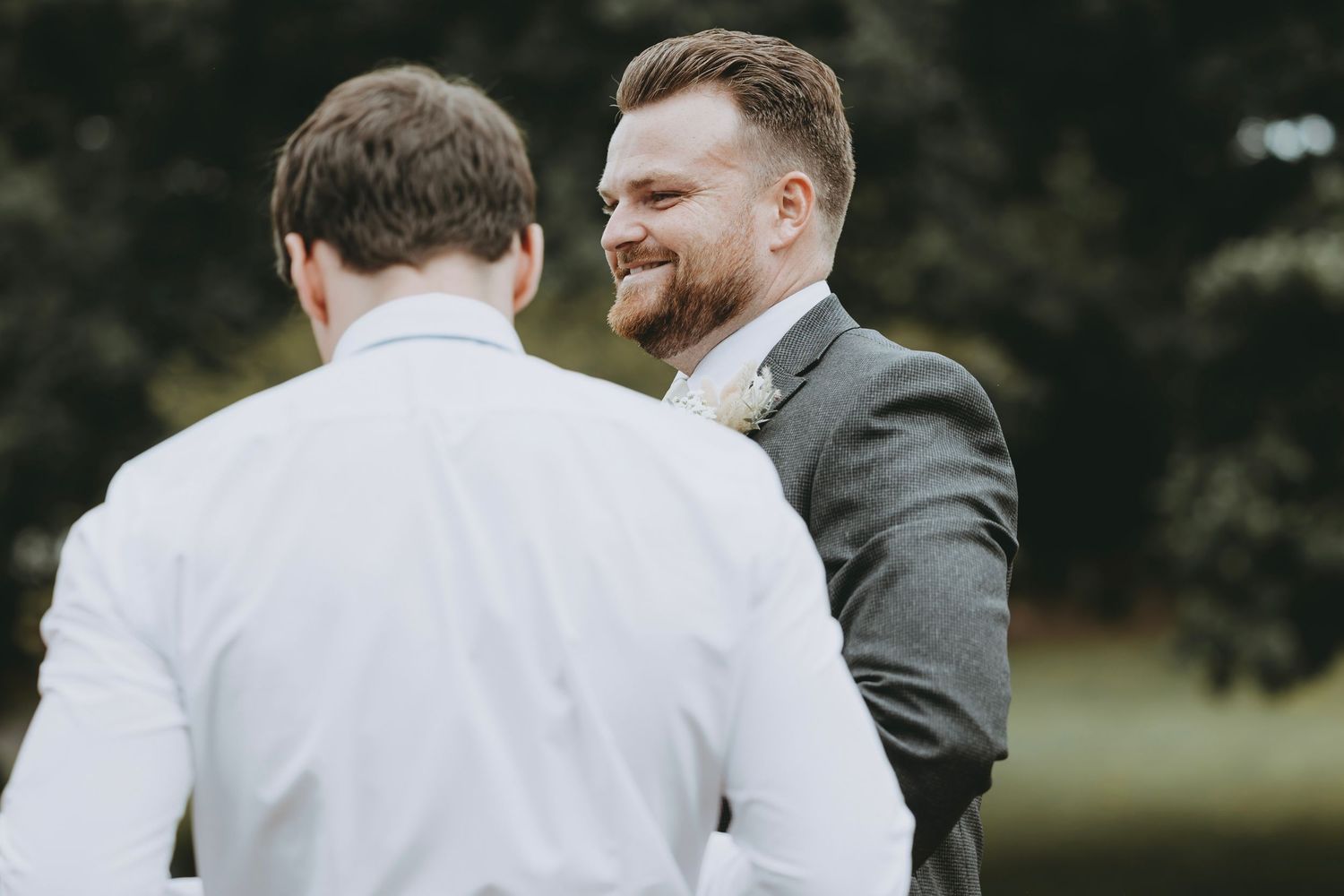 Wedding party members in formal attire stand together during an outdoor celebration.