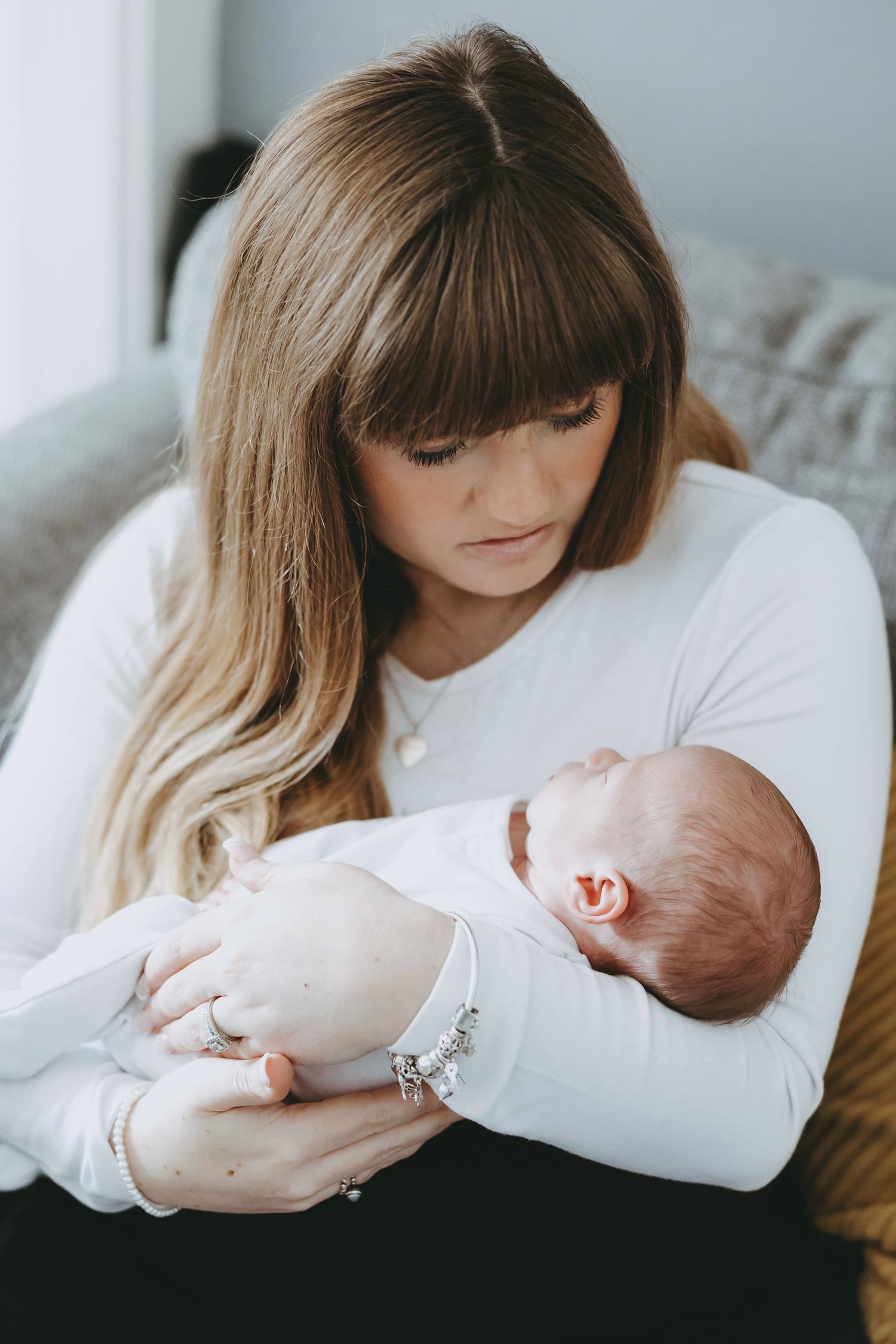 A tender moment between parent and newborn baby in white clothing against a light background.