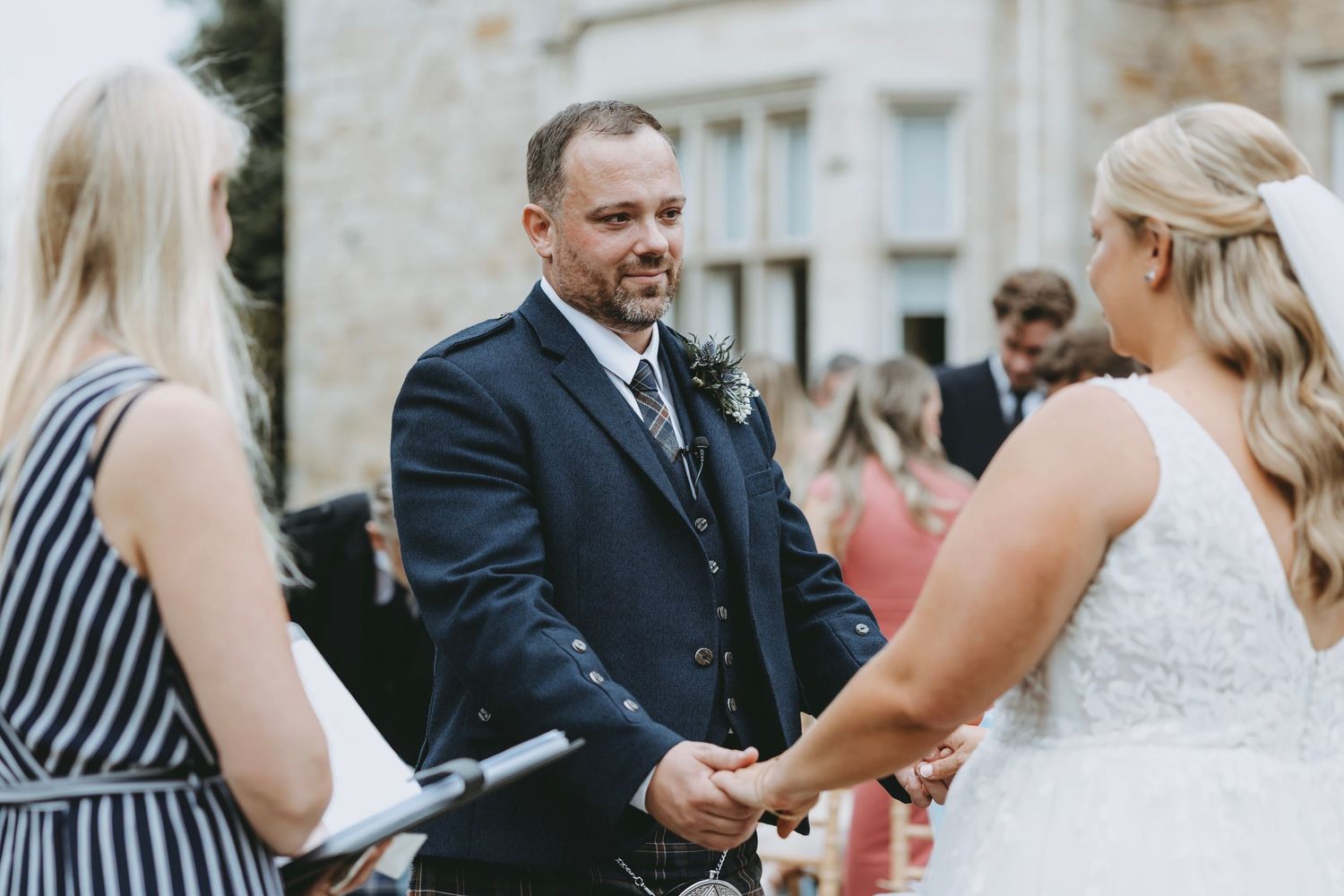 Wedding celebration with guests in formal attire and traditional Scottish kilts.