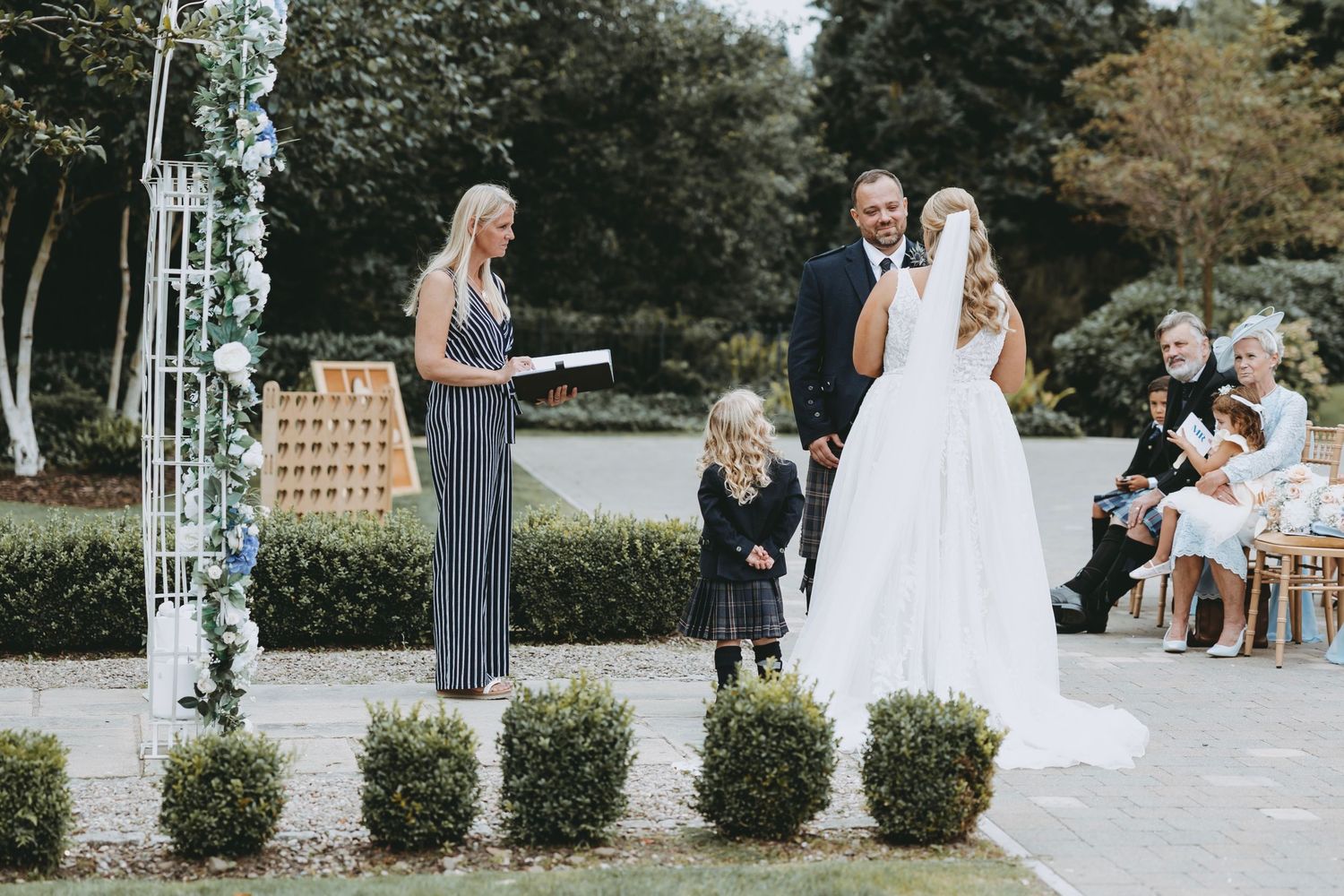 A series of outdoor wedding ceremony moments showing a bride in a white dress and guests gathered at a stone venue.