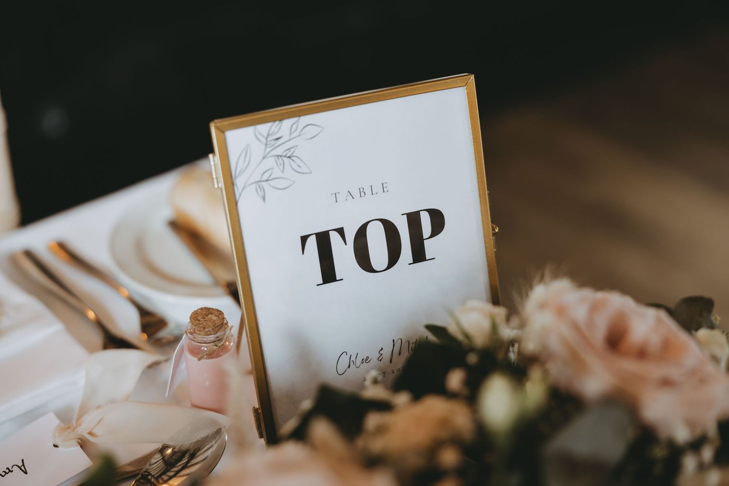 Decorative table numbers in gold frames with floral accents at wedding reception.