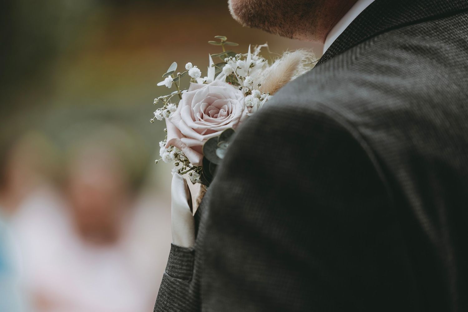 Close-up view of formal suit jacket with pink rose boutonniere.
