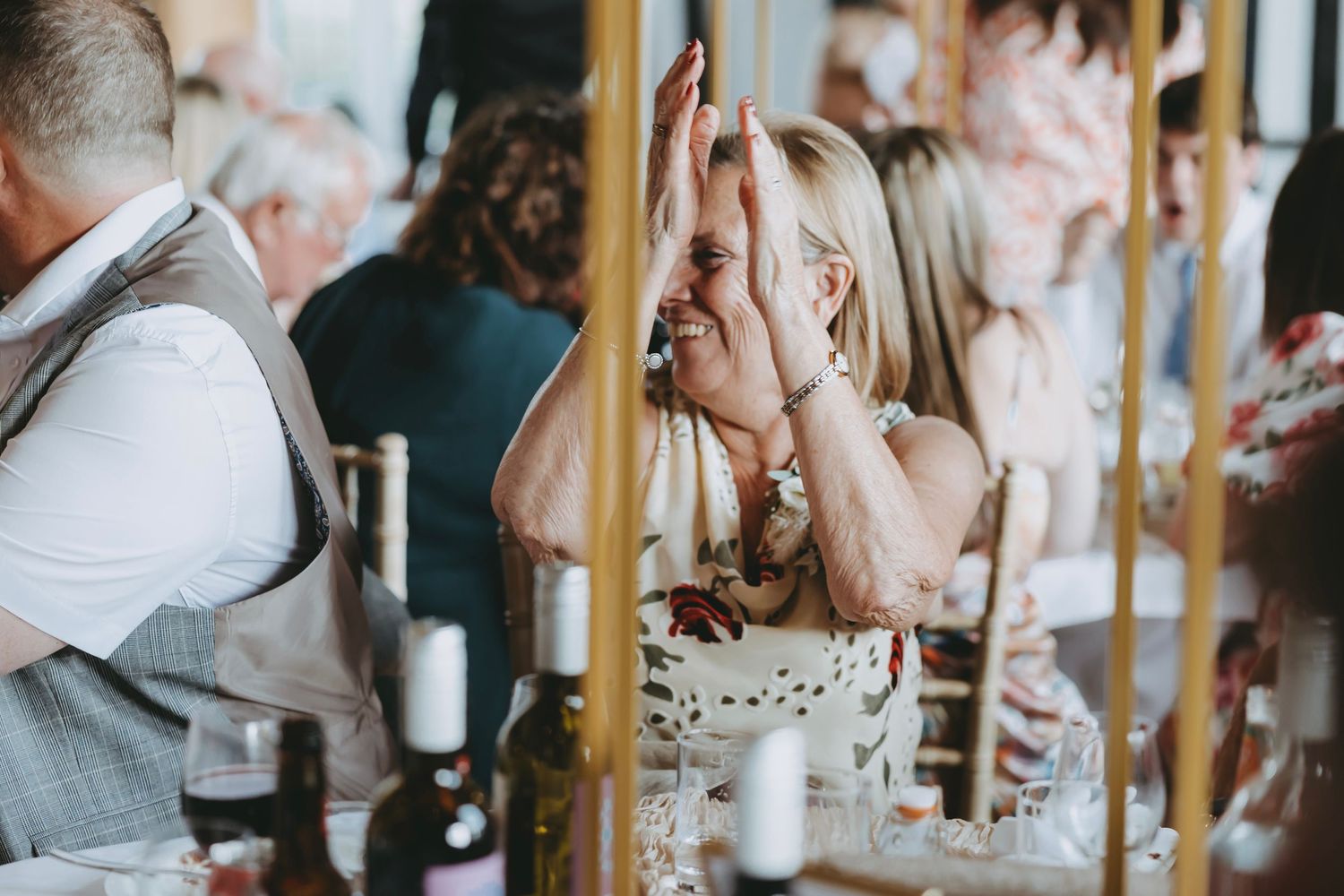 Wedding guests raise their glasses in celebration during an indoor reception toast.