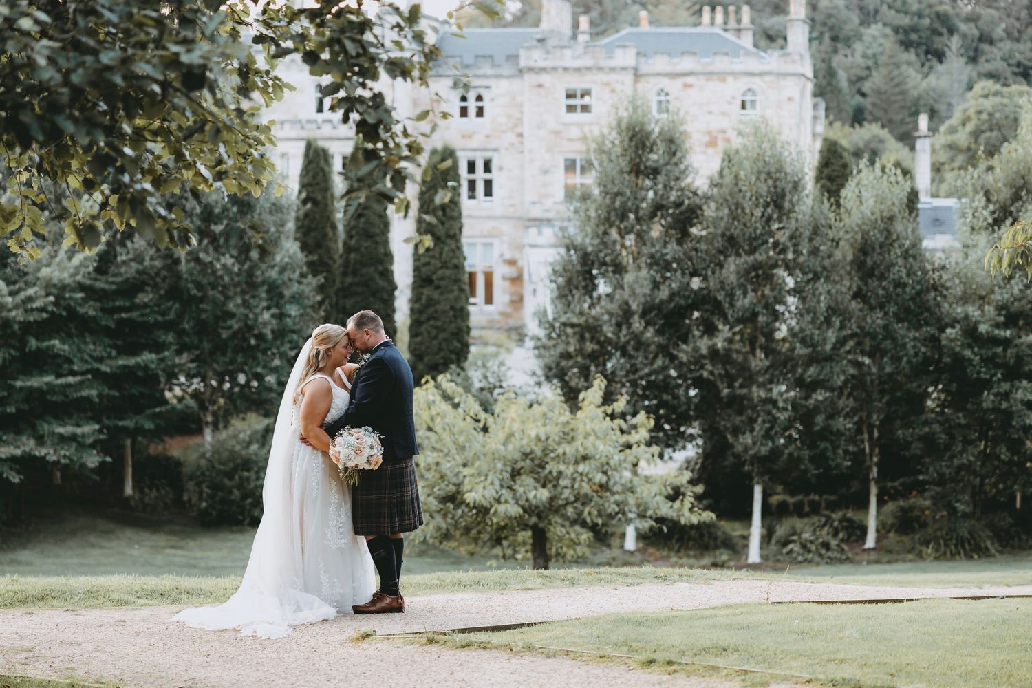 Newlyweds walking hand in hand through a beautiful outdoor garden landscape.